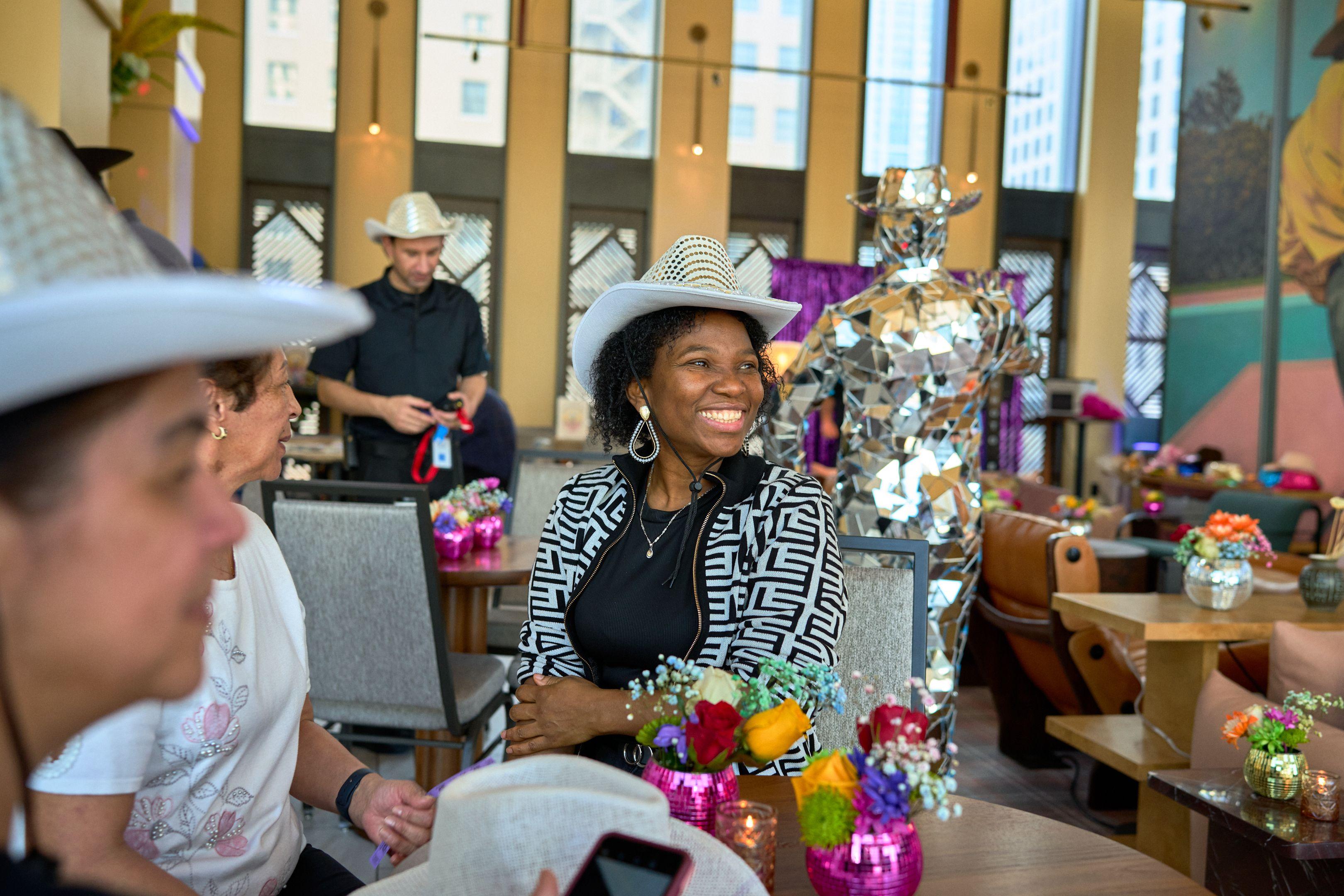 Guest in a white cowboy hat beside a mirrored mosaic sculpture — Business Parties photography, Austin A guest in a white cowboy hat beside a mirrored mosaic sculpture at a western-themed corporate party.