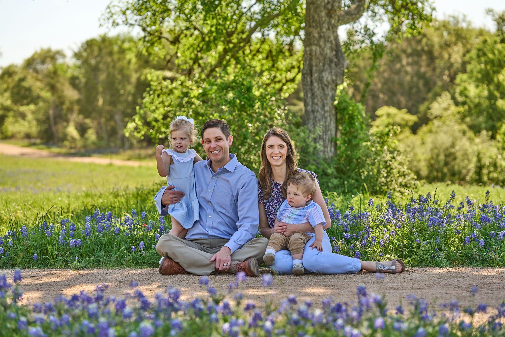 Family of four seated on a path through a bluebonnet field — Circle C Ranch photography, Austin A family of four seated on a path through a bluebonnet field.