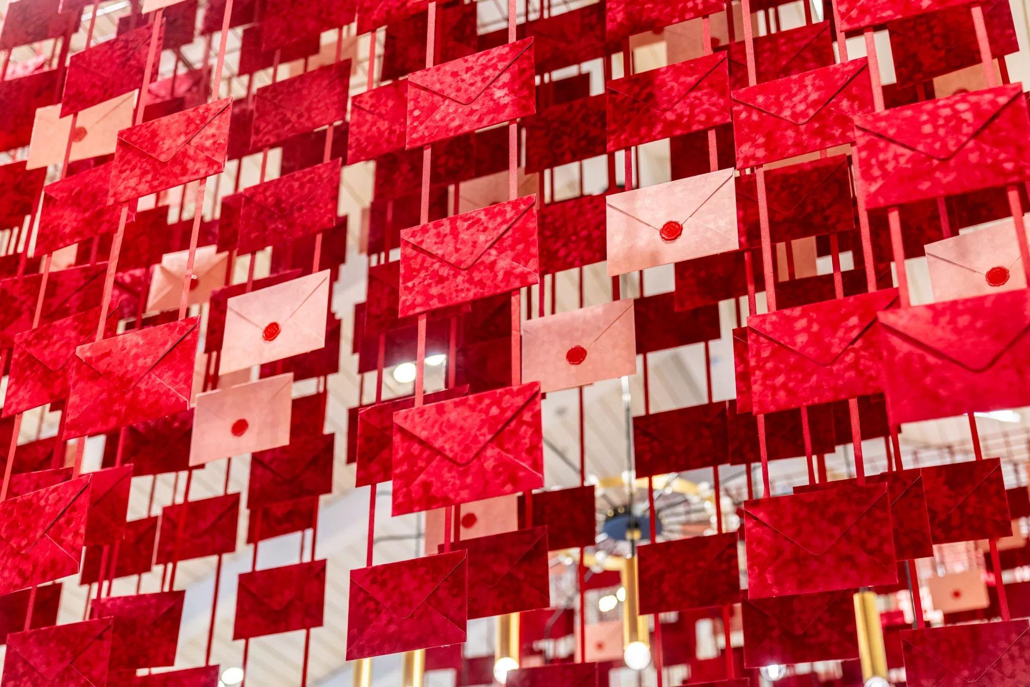 Ceiling installation of hundreds of red and pink wax-sealed envelopes hung on ribbons — E-commerce & apparel photography, Austin Ceiling installation of hundreds of red and pink wax-sealed envelopes hung on ribbons in a retail space