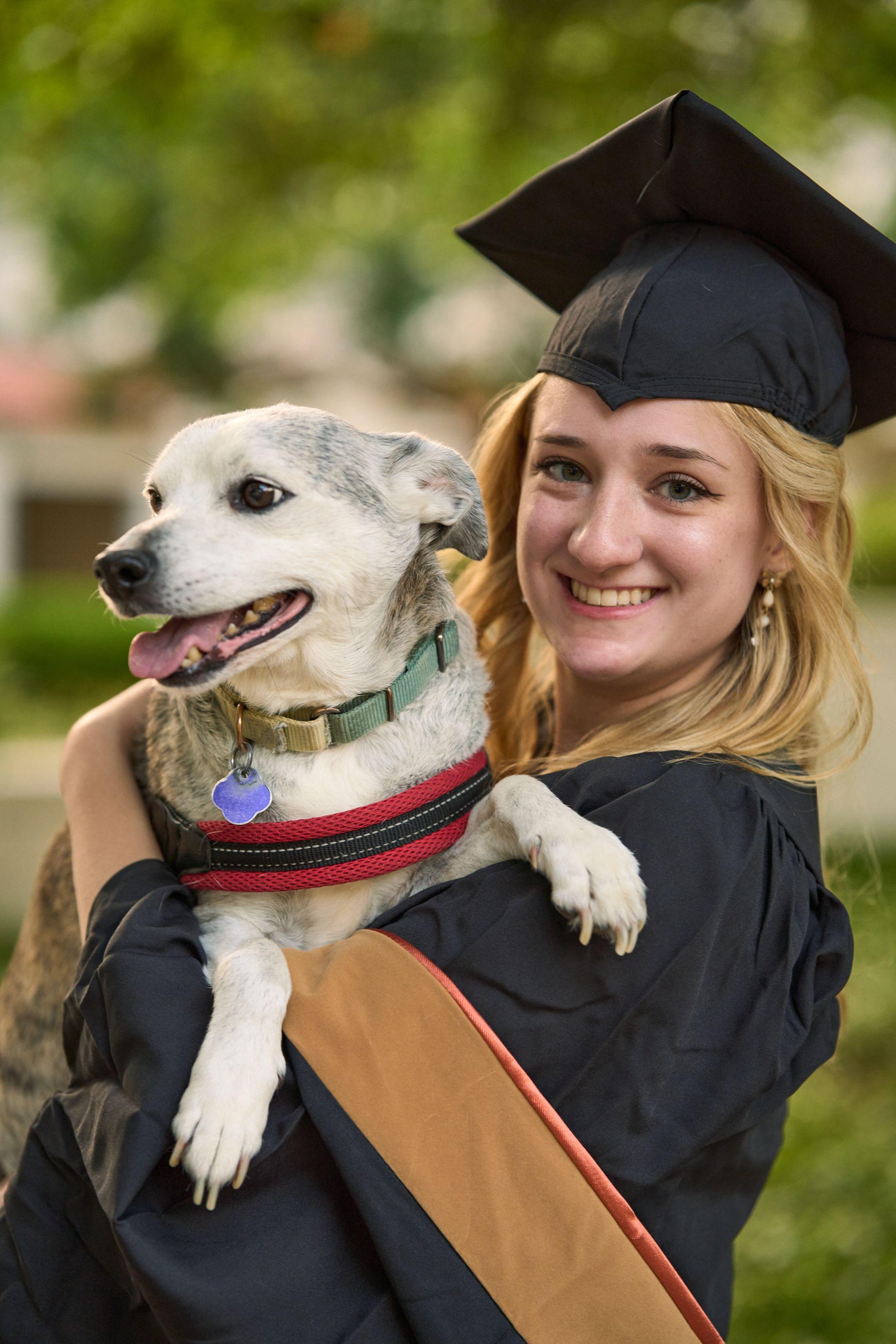 Graduate in cap and gown holding her dog, both facing camera — Graduation & Prom photography, Austin A graduate in cap and gown holding her dog, both facing camera.
