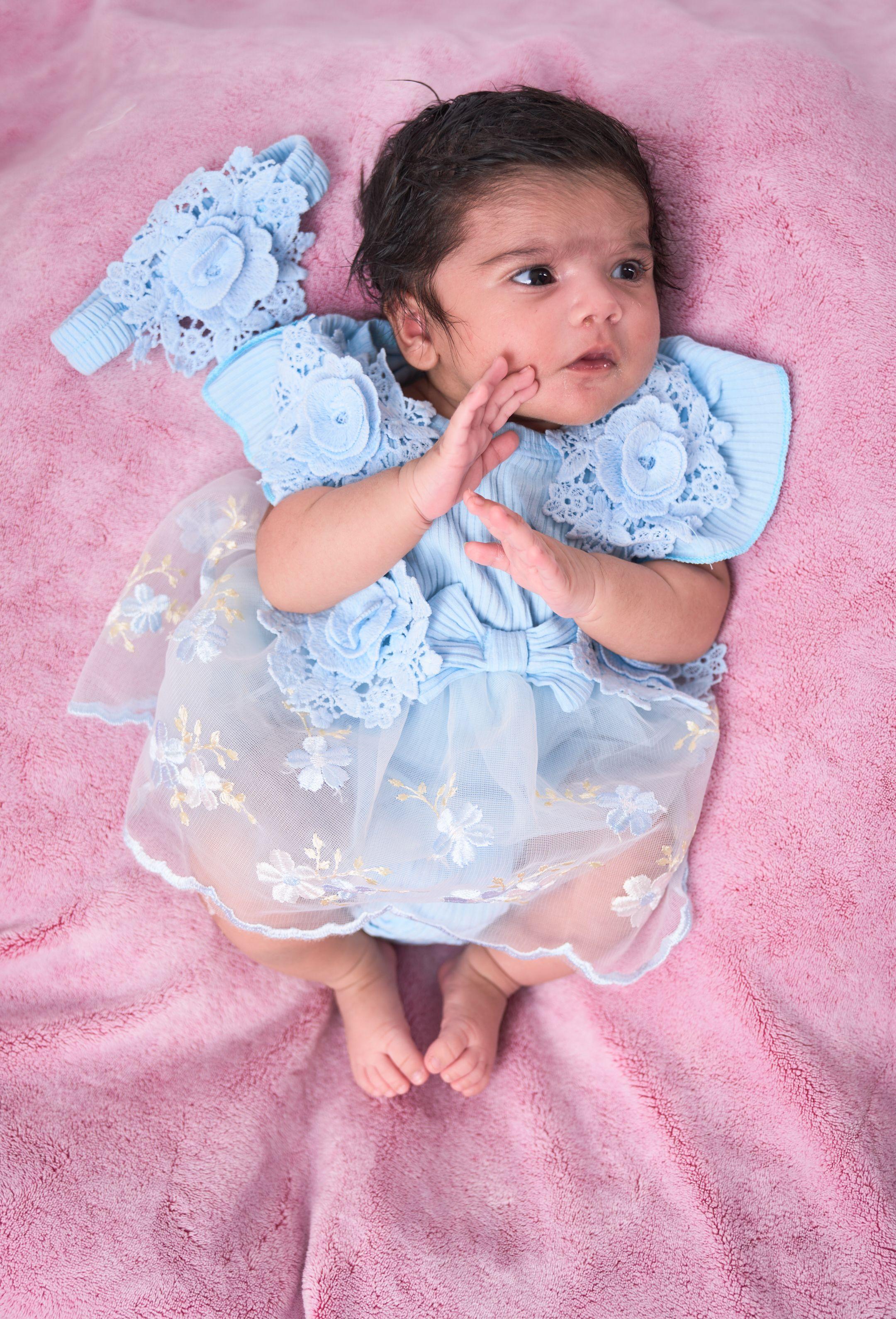 Baby in a pale blue lace dress and headband lying on a pink blanket — Newborn photography, Austin A baby in a pale blue lace dress and headband lying on a pink blanket.