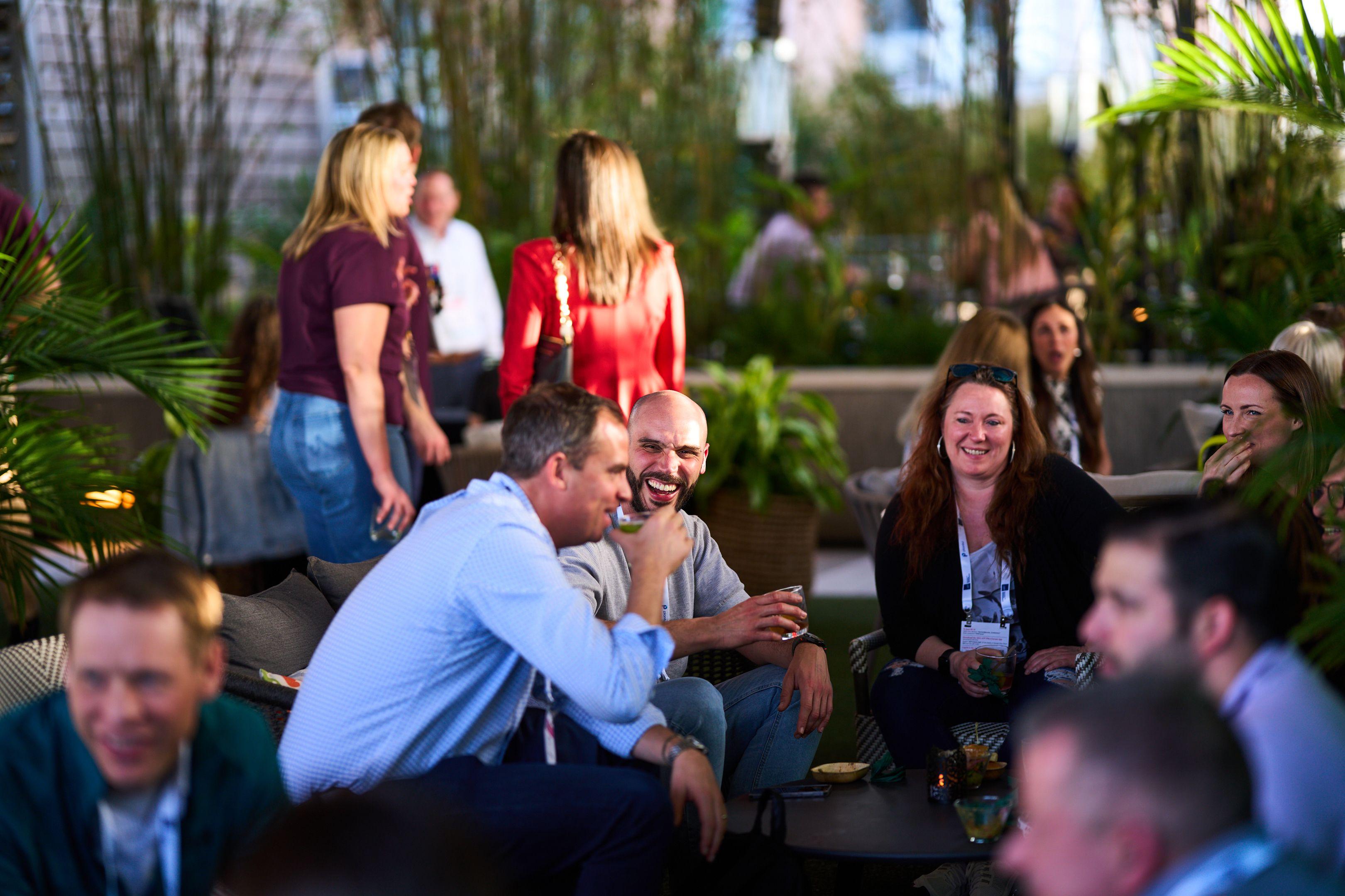 Colleagues seated around low tables on a rooftop patio, mid-conversation with drinks — Business Parties photography, Austin Colleagues seated around low tables on a rooftop patio, mid-conversation with drinks.