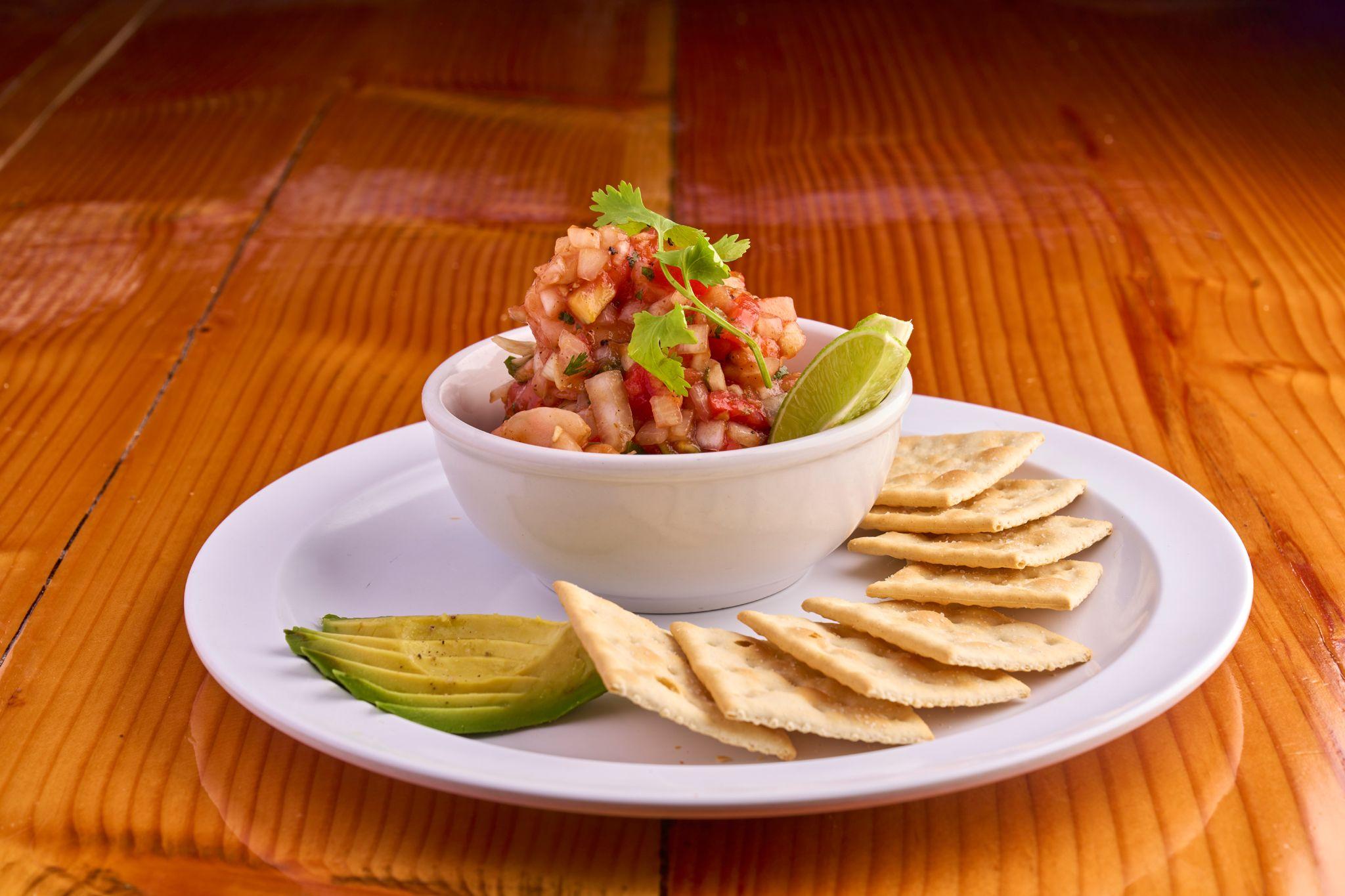 Bowl of ceviche with avocado and pita chips on a white plate — Food & restaurant photography, Austin A bowl of ceviche with avocado and pita chips on a white plate.
