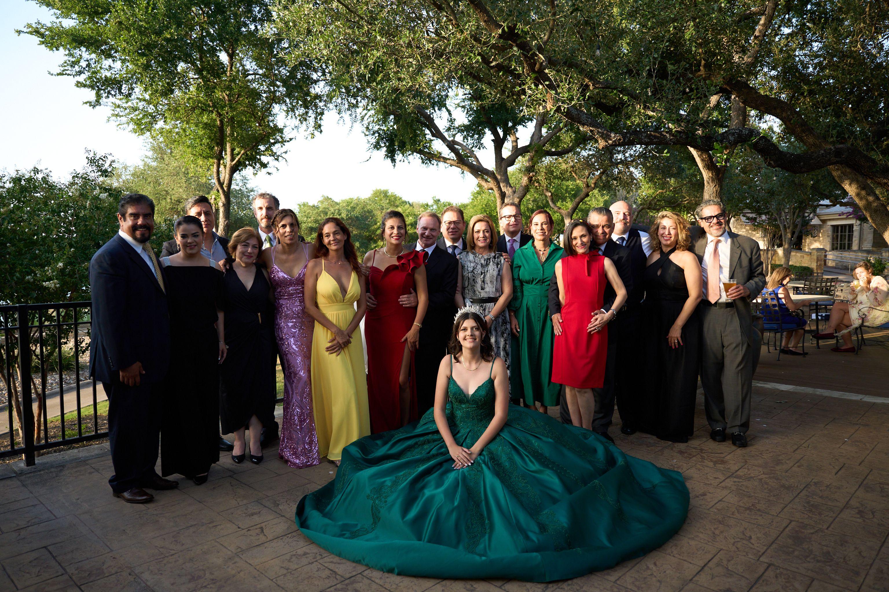 Large family in formal dress gathered on steps, a young woman in a green ballgown seated — Family Portraits photography, Austin A large family in formal dress gathered on steps, a young woman in a green ballgown seated in front.