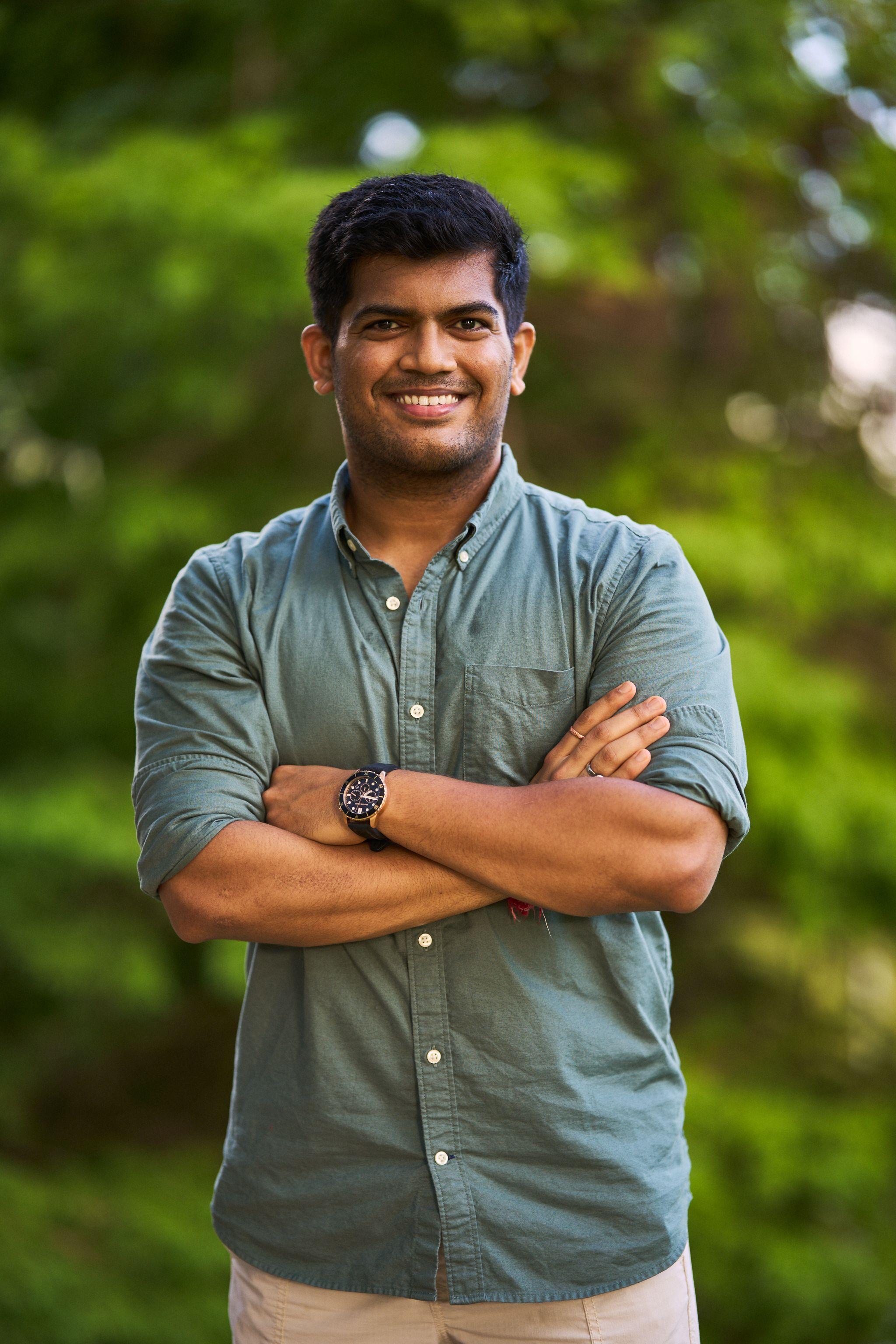 Man in a green shirt standing with his arms crossed under the trees at Mills Pond — Mills Pond photography, Austin A man in a green shirt standing with his arms crossed under the trees at Mills Pond