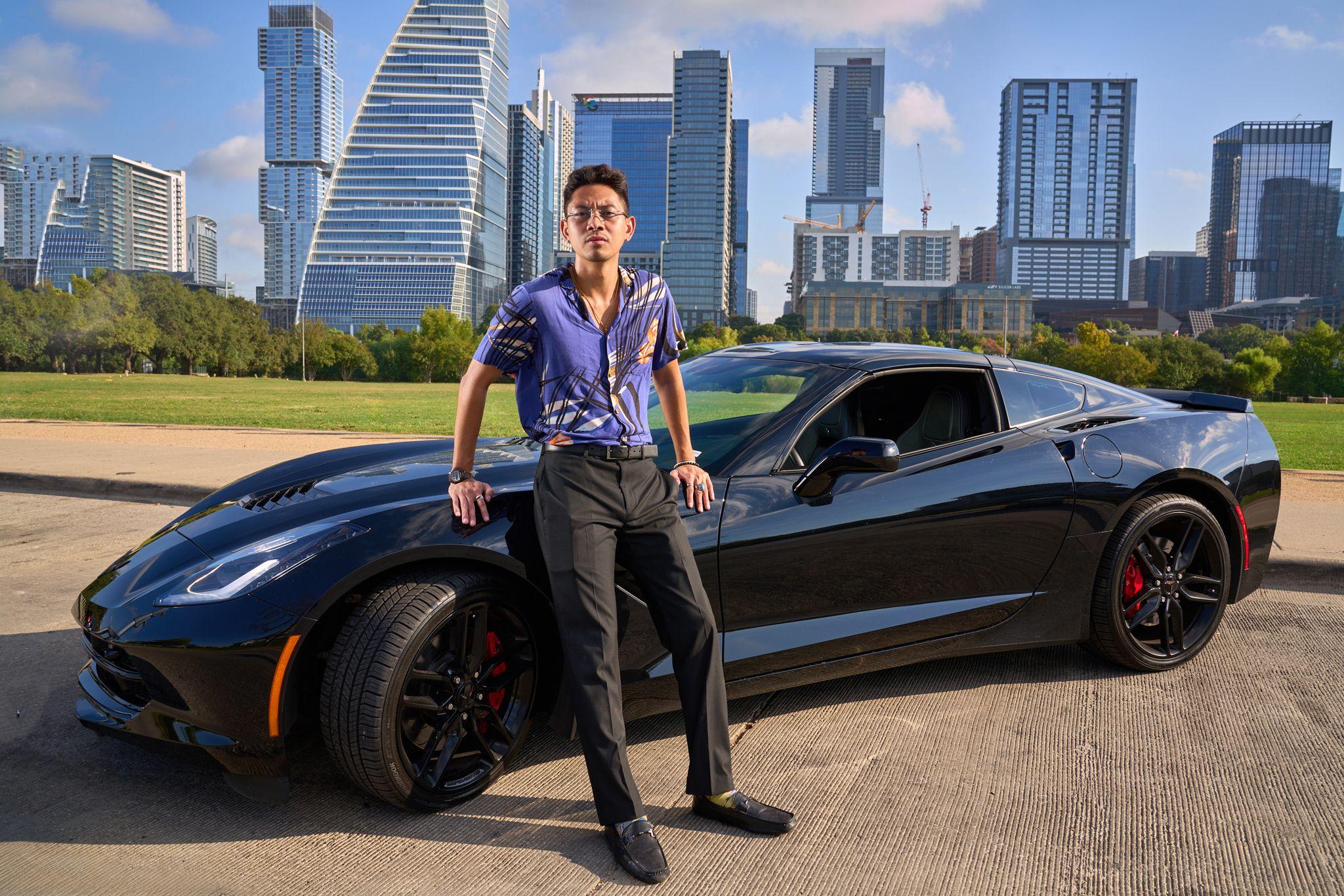 Man in a purple shirt leaning on a black sports car with the Austin skyline behind him — Portrait photography, Austin A man in a purple shirt leaning on a black sports car with the Austin skyline behind him.