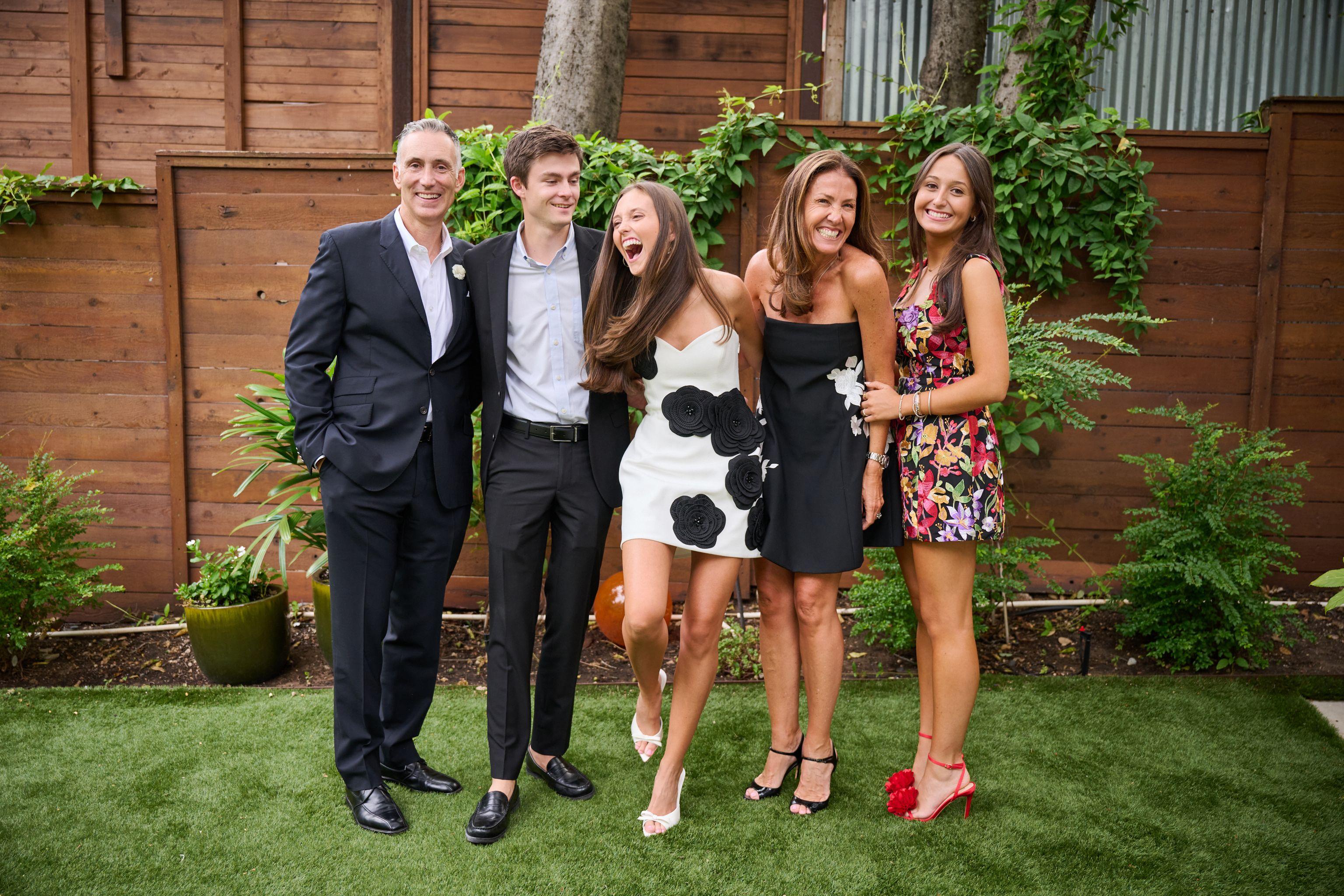 Family group in formal dress posed together on a lawn, one laughing mid-photo — Formal Celebrations photography, Austin A family group in formal dress posed together on a lawn, one laughing mid-photo.