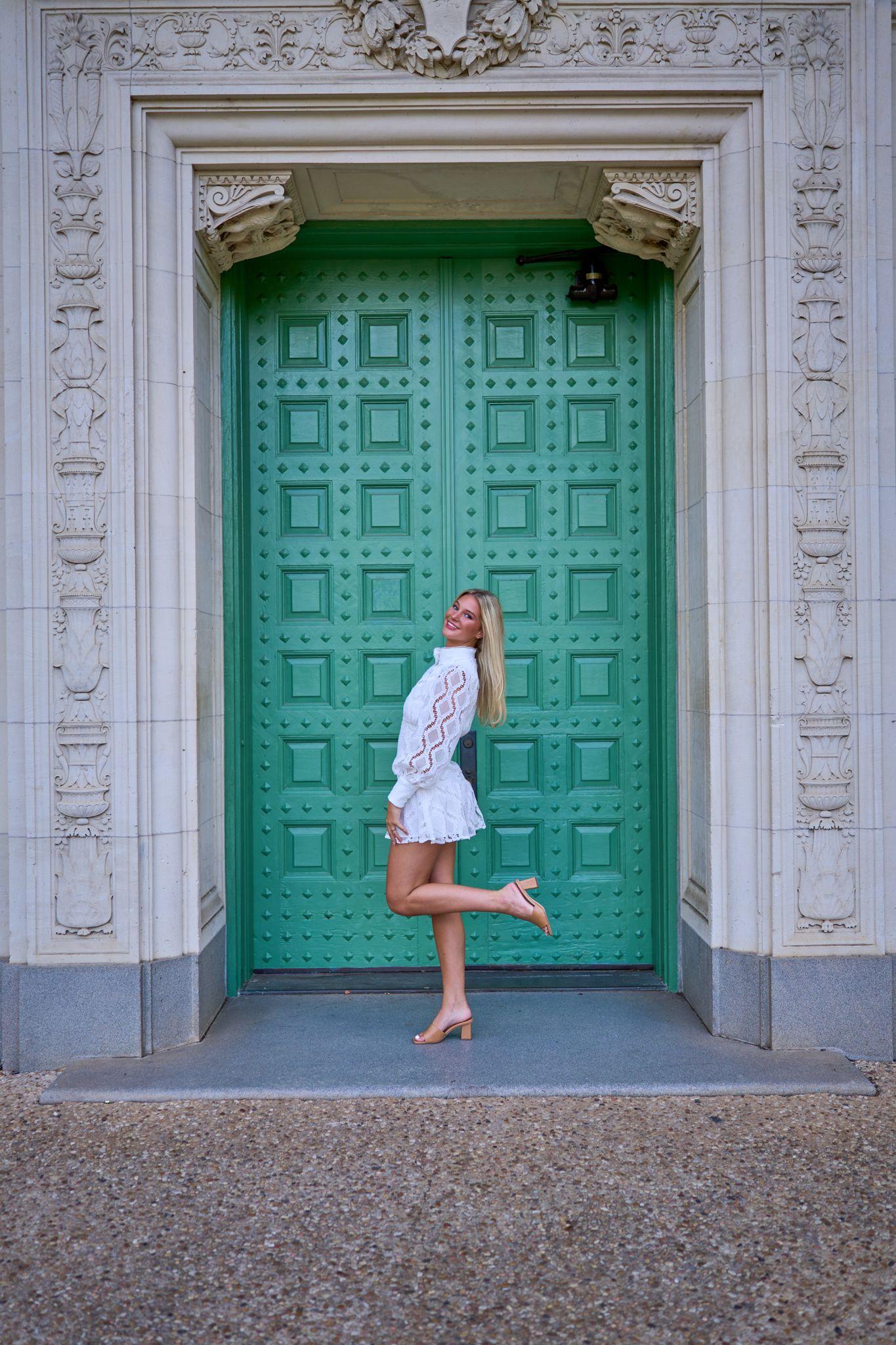 Graduate posing against the tall green bronze doors of a campus building — UT Austin photography, Austin A graduate posing against the tall green bronze doors of a campus building.