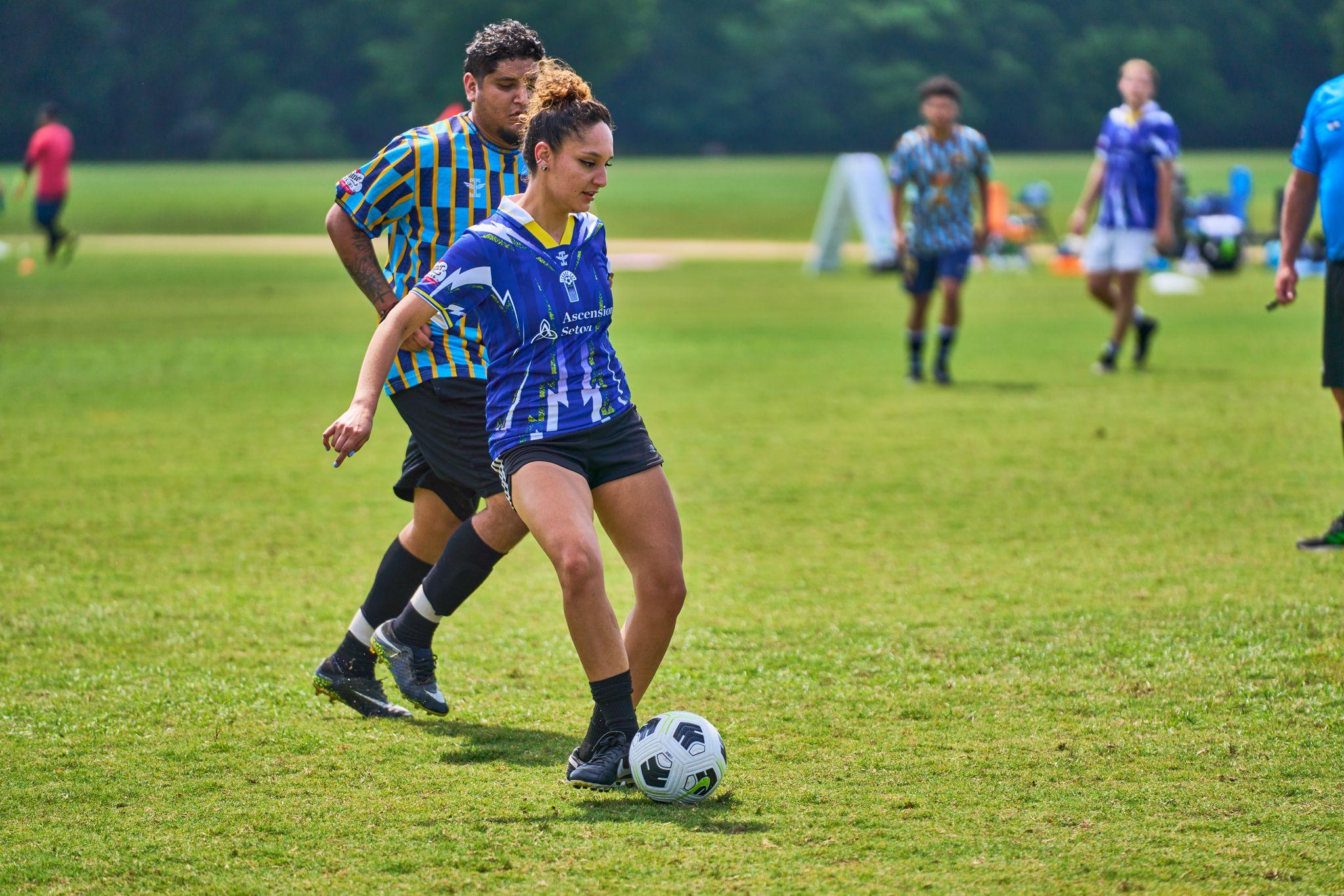 Player in a blue kit driving forward with the ball as opponents track back — Sports photography, Austin Player in a blue kit driving forward with the ball as opponents track back