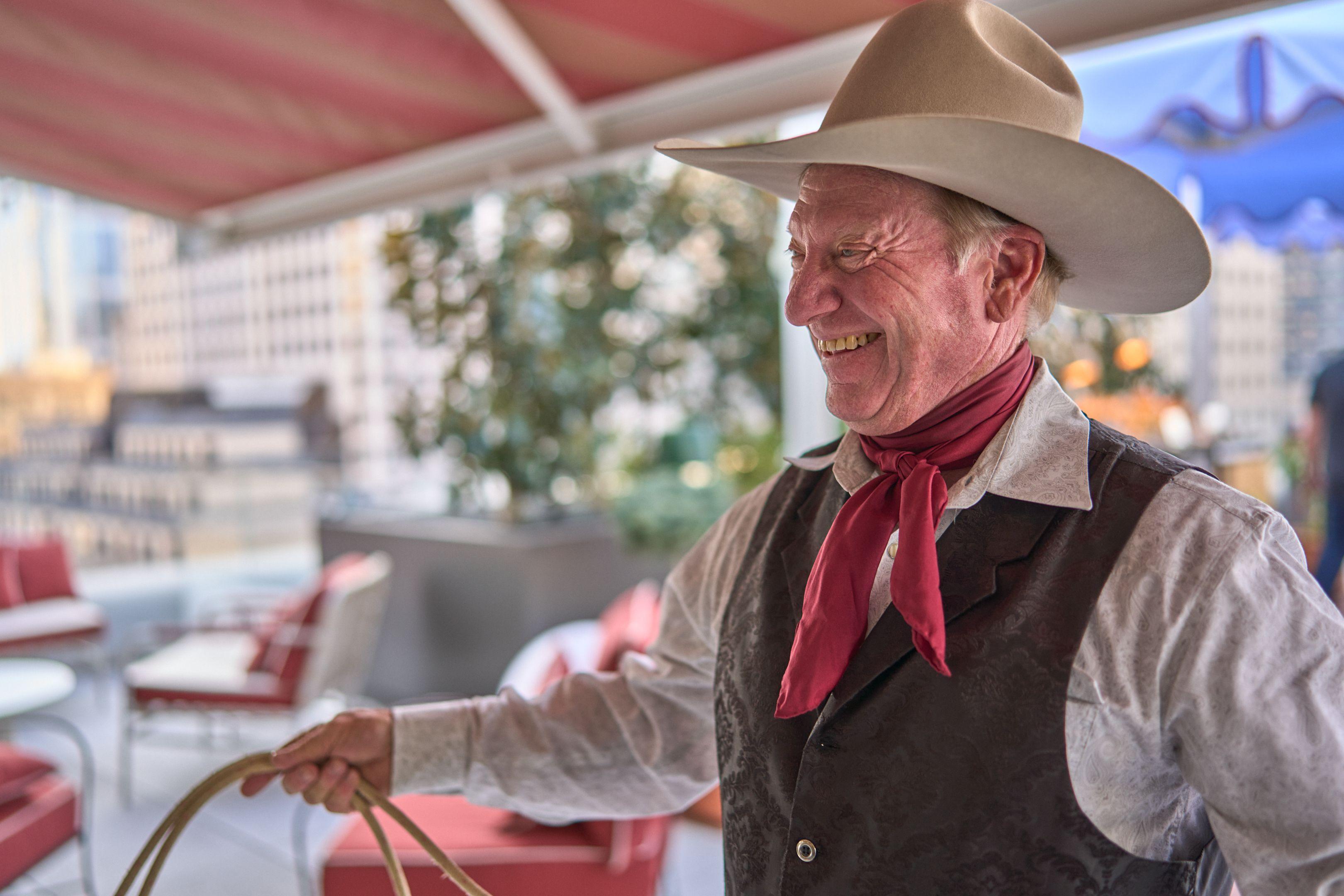 Rope performer in a cowboy hat mid-trick, the lasso blurred in front of him — Business Parties photography, Austin A rope performer in a cowboy hat mid-trick, the lasso blurred in front of him.