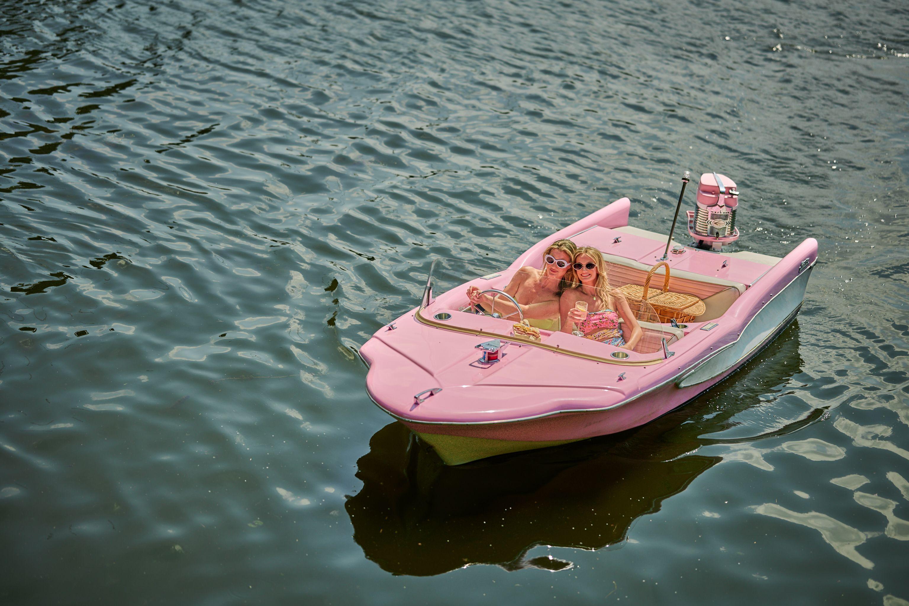 Pink vintage speedboat carrying two passengers on open green water — Bachelor & Bachelorette photography, Austin A pink vintage speedboat carrying two passengers on open green water.