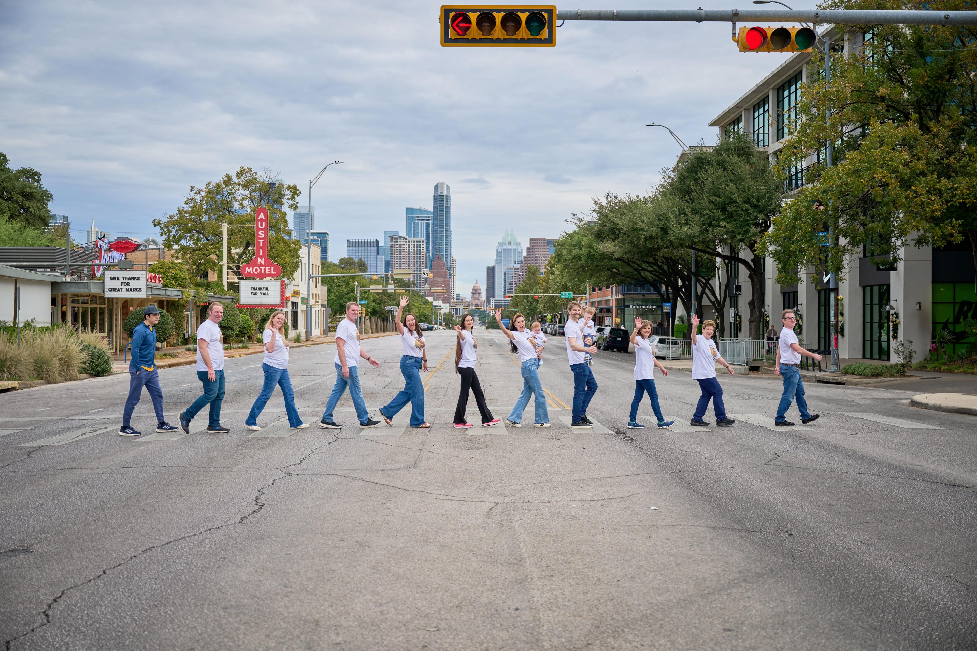 Family strung out across a Congress Avenue crosswalk, the Austin skyline in the distance — Family Portraits photography, Austin A family strung out across a Congress Avenue crosswalk, the Austin skyline in the distance.