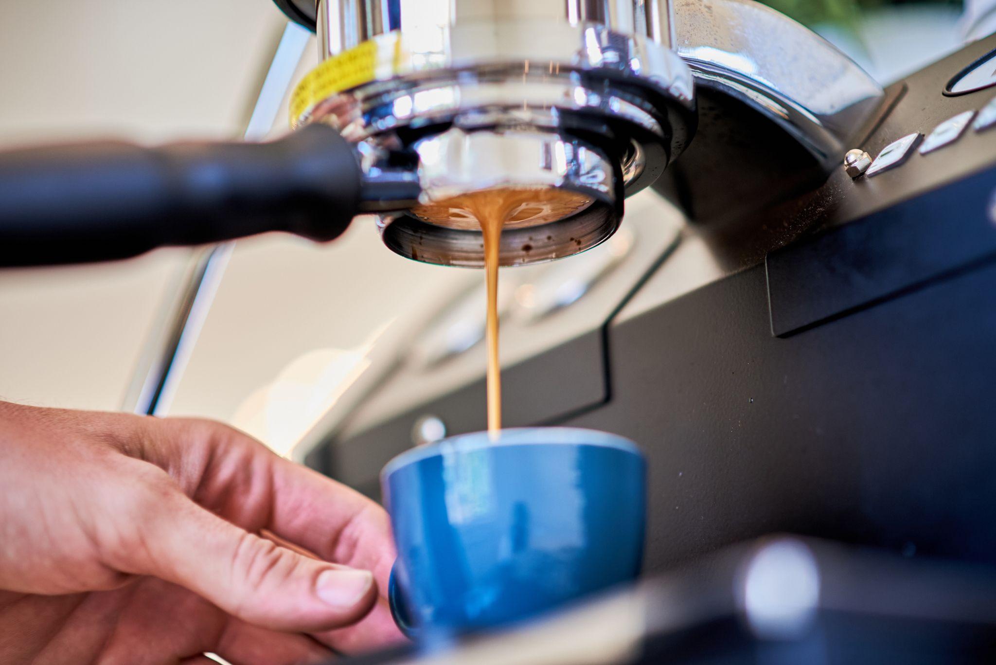 Espresso shot pulling from a machine into a blue cup — Product photography, Austin An espresso shot pulling from a machine into a blue cup.