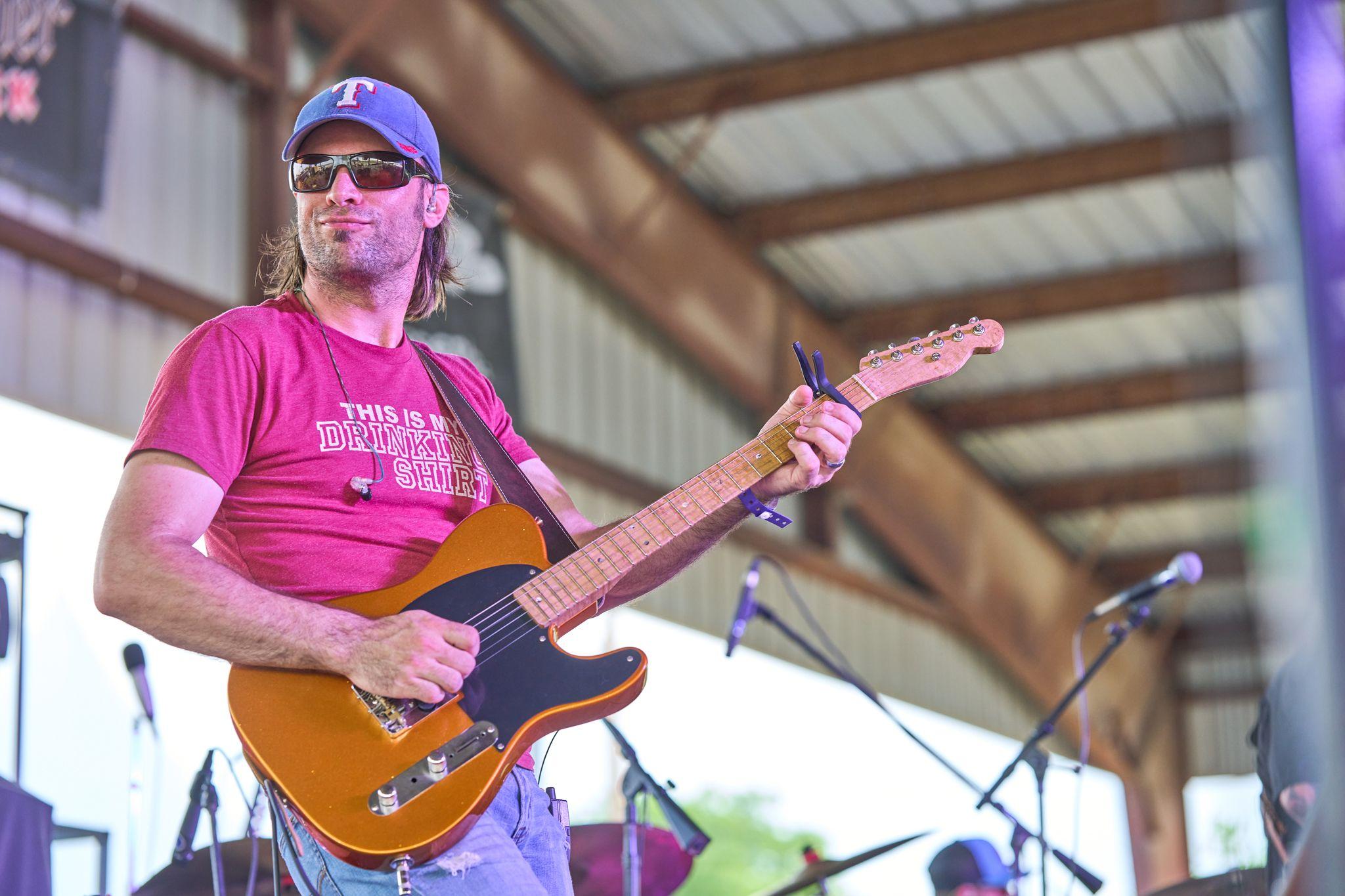 Guitarist playing a hollow-body electric under a metal pavilion roof — Live music photography, Austin A guitarist playing a hollow-body electric under a metal pavilion roof.