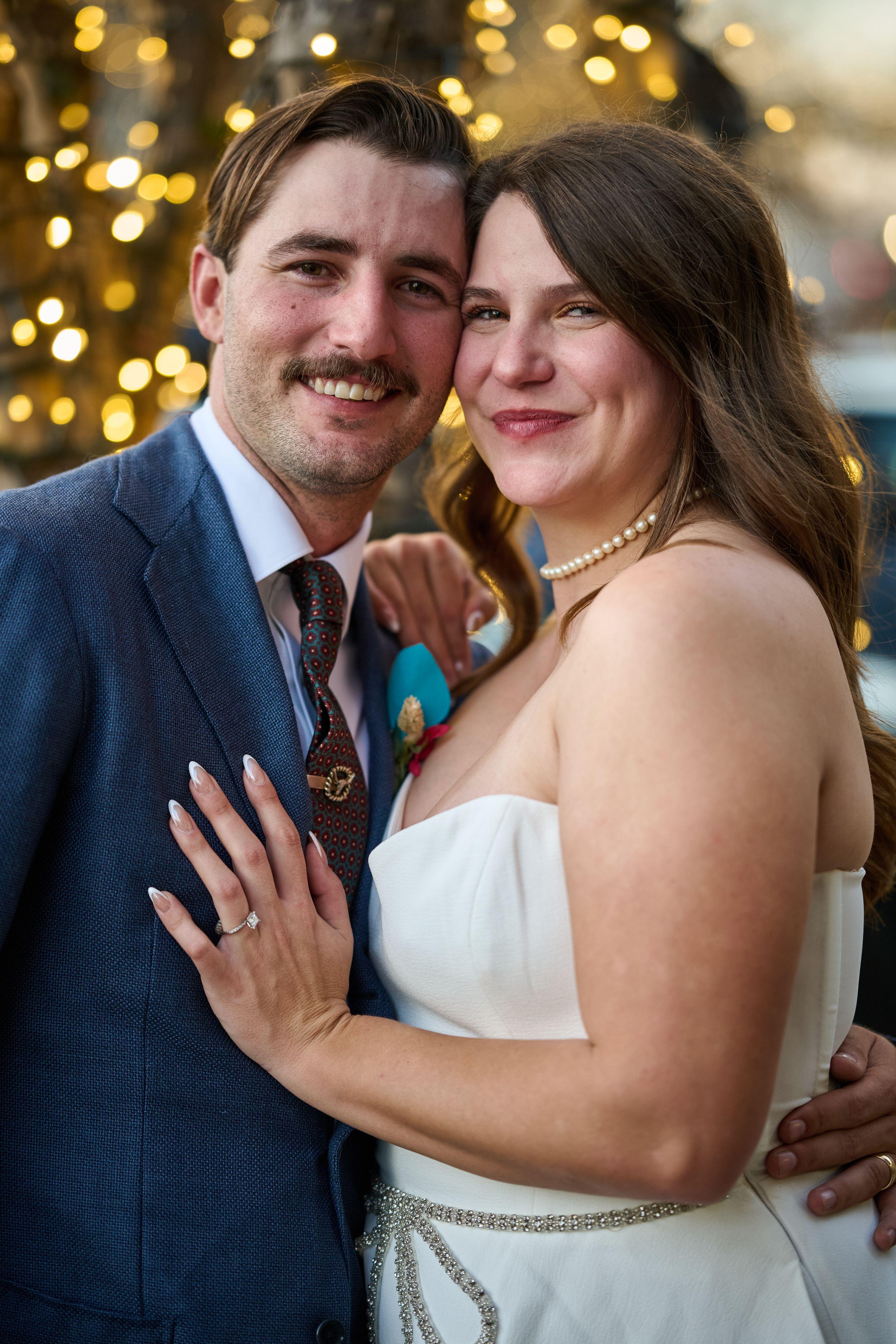 Couple embracing under warm string lights, her hand resting on his lapel — Georgetown Downtown photography, Austin A couple embracing under warm string lights, her hand resting on his lapel.