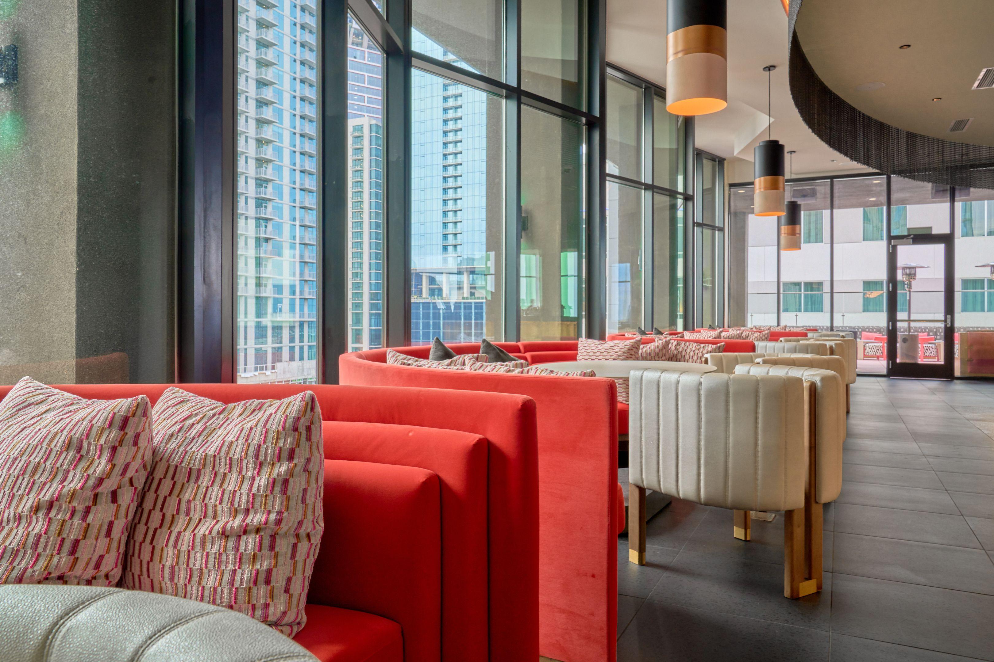 Red curved booths in a rooftop restaurant, downtown Austin towers visible through the windows — Food & restaurant photography, Austin Red curved booths in a rooftop restaurant, downtown Austin towers visible through the windows.