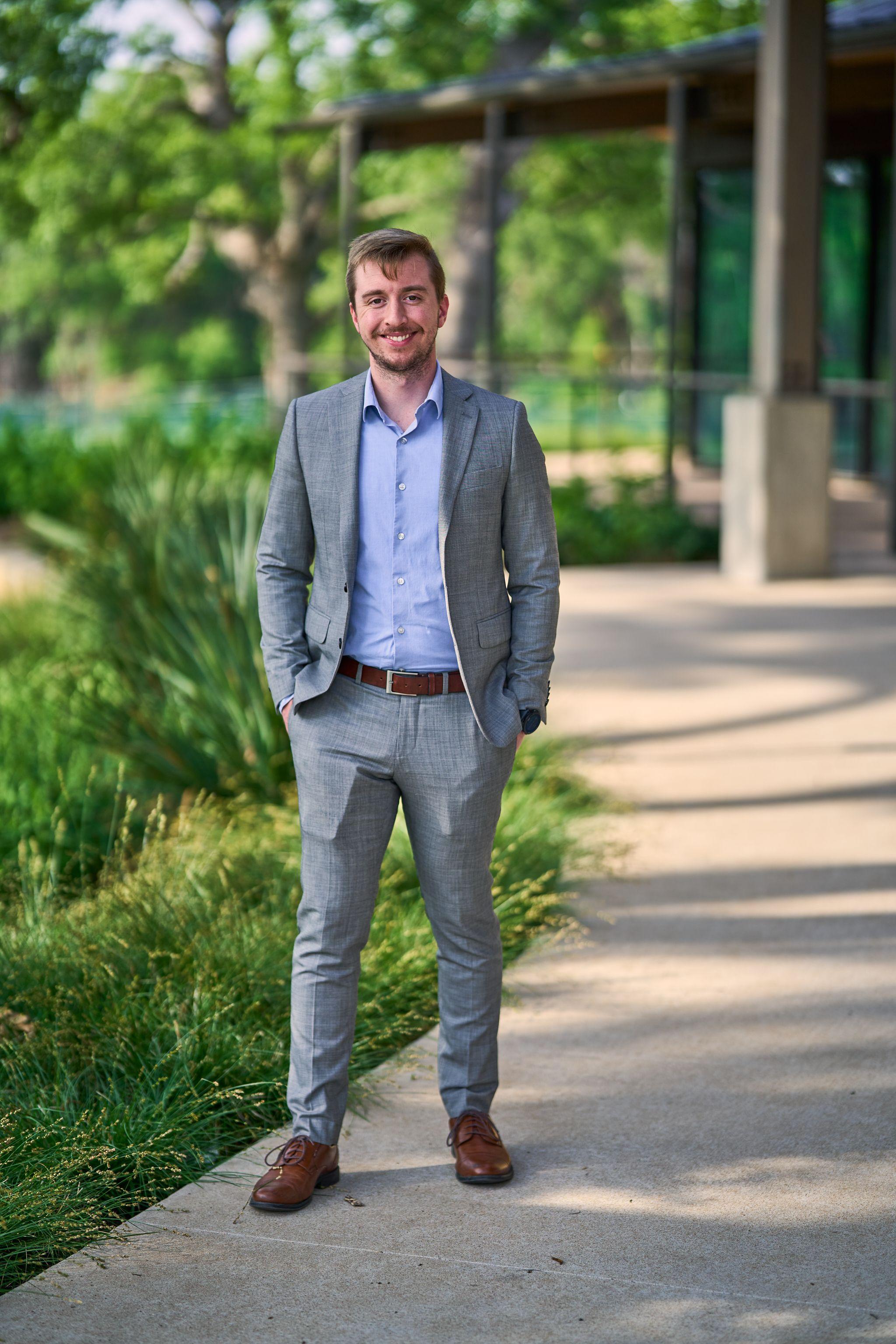 Man in a gray suit standing full length on the path outside the Cedar Park Public Library — Cedar Park Public Library photography, Austin A man in a gray suit standing full length on the path outside the Cedar Park Public Library