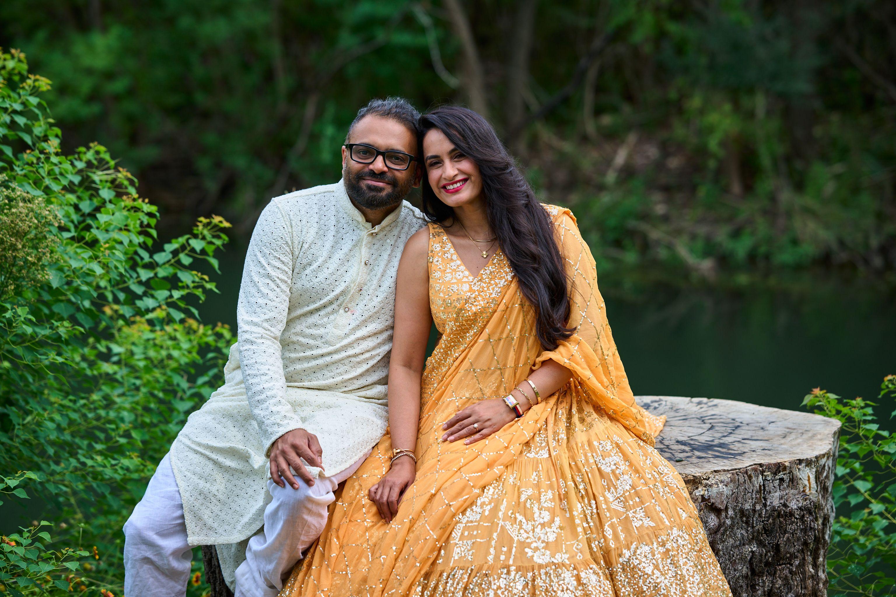 Couple seated on stone at the Cedar Park library, the man in a cream kurta and the woman — Cedar Park Public Library photography, Austin A couple seated on stone at the Cedar Park library, the man in a cream kurta and the woman in a gold lehenga