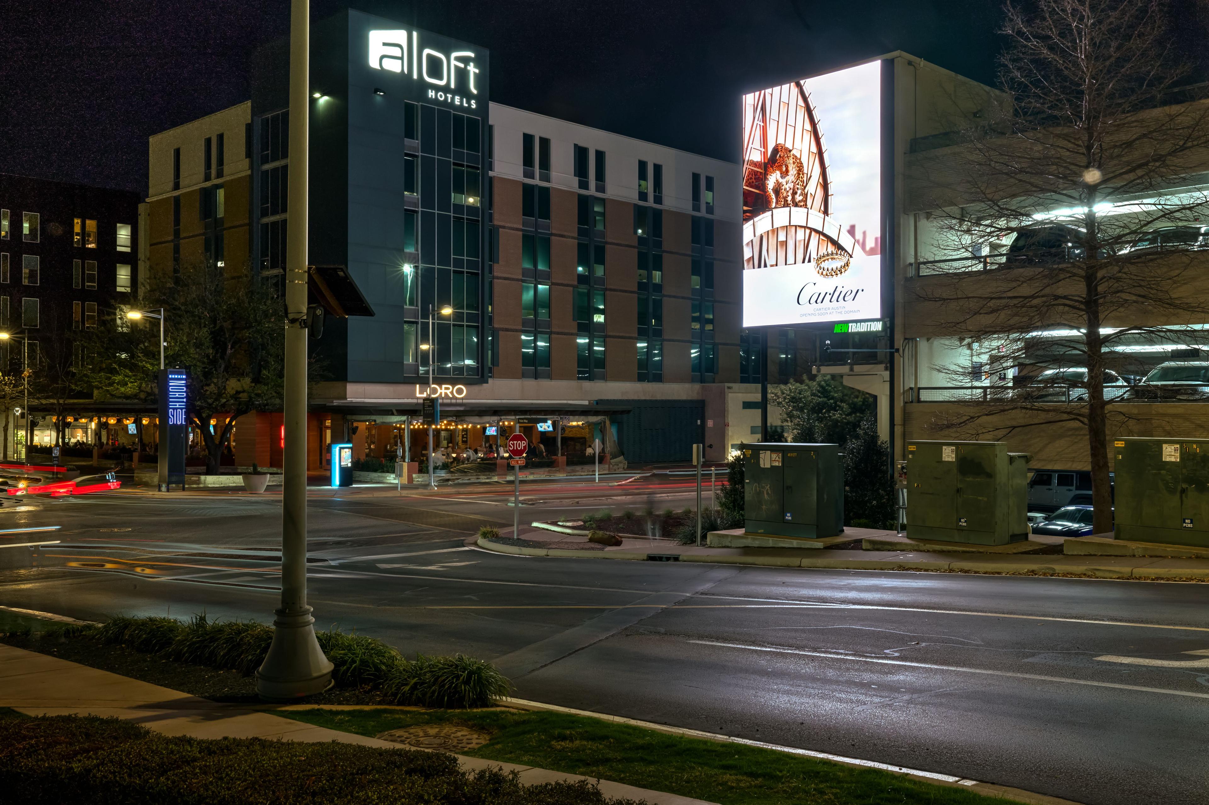 Illuminated Cartier digital billboard glowing beside the Aloft hotel at night in The Domain — Outdoor media photography, Austin An illuminated Cartier digital billboard glowing beside the Aloft hotel at night in The Domain.