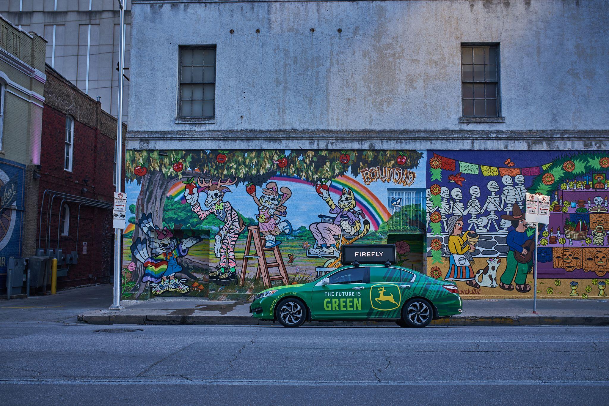 Green John Deere-wrapped car reading 'THE FUTURE IS GREEN' parked — Brand Collaborations photography, Austin A green John Deere-wrapped car reading 'THE FUTURE IS GREEN' parked in front of a large painted mural on an east Austin wall.