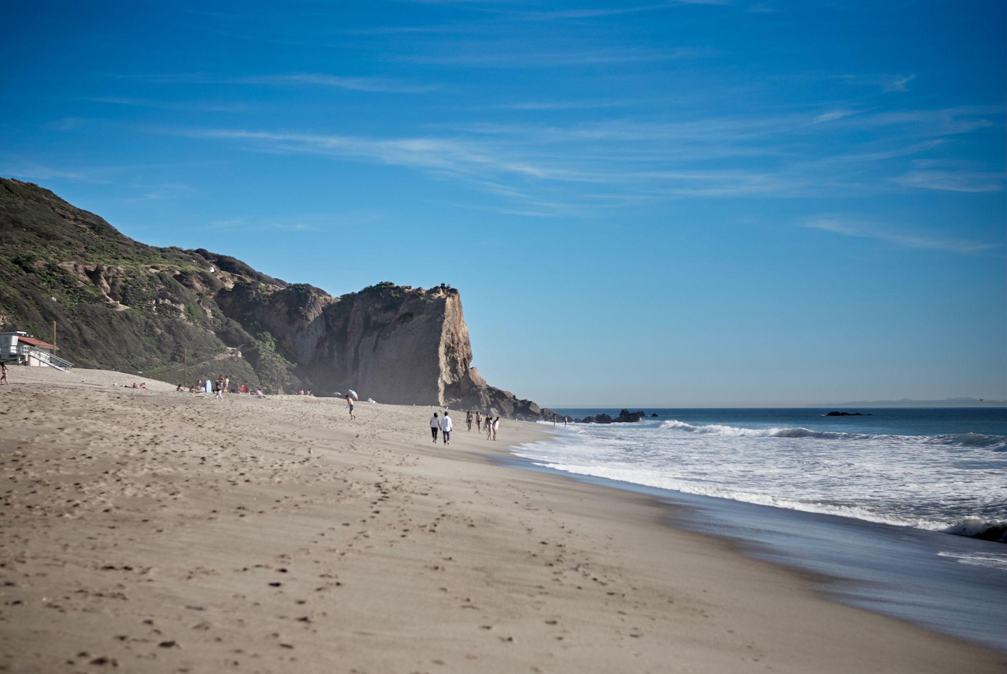 Wide empty beach beneath a headland cliff — Adventure & outdoor photography, Austin A wide empty beach beneath a headland cliff.
