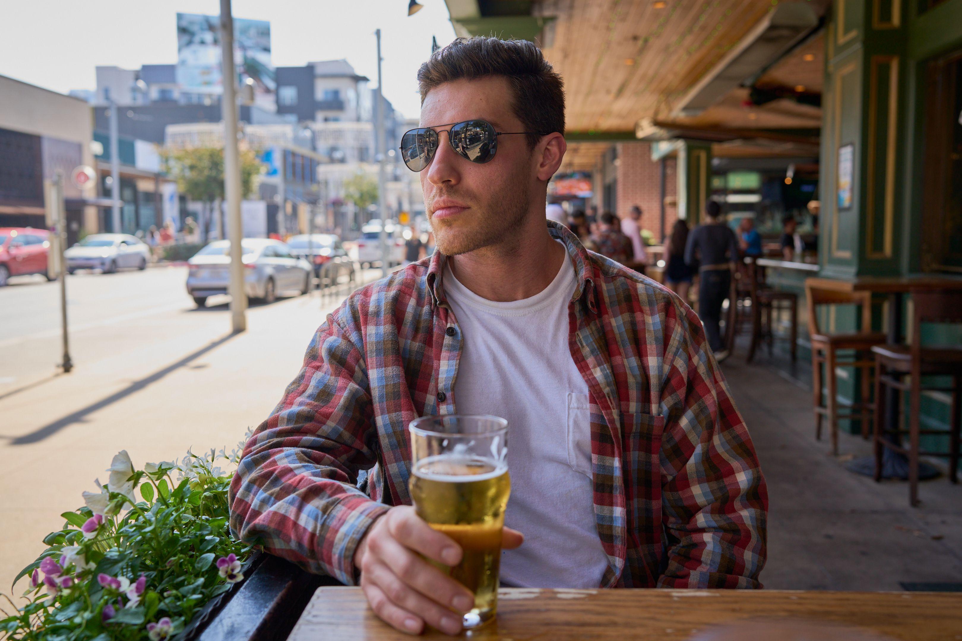 Man in sunglasses and a plaid shirt holding a beer on a patio — Portrait photography, Austin A man in sunglasses and a plaid shirt holding a beer on a patio.