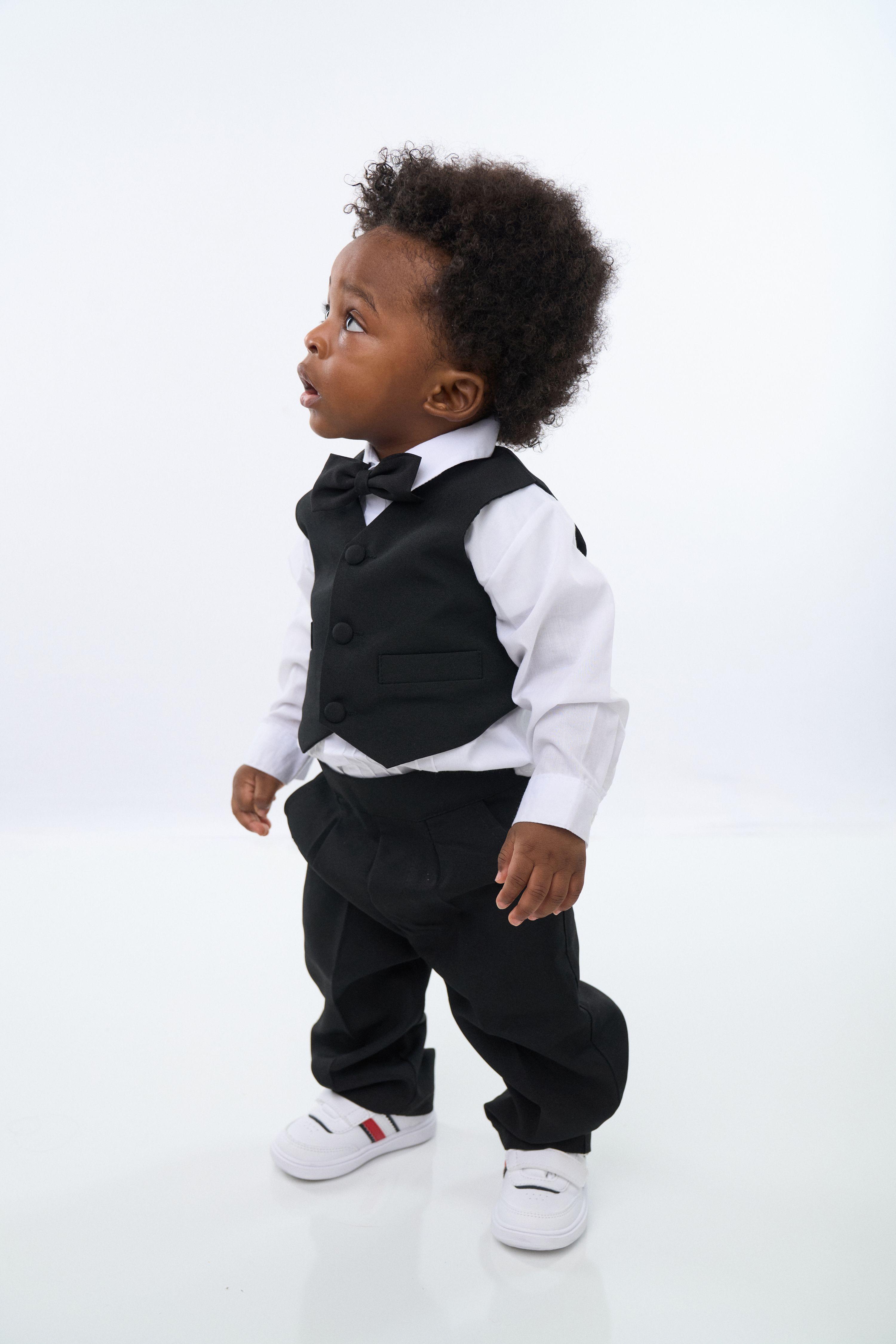 Small boy in a black waistcoat and bow tie walking on a white studio floor — Kids Portraits photography, Austin A small boy in a black waistcoat and bow tie walking on a white studio floor.