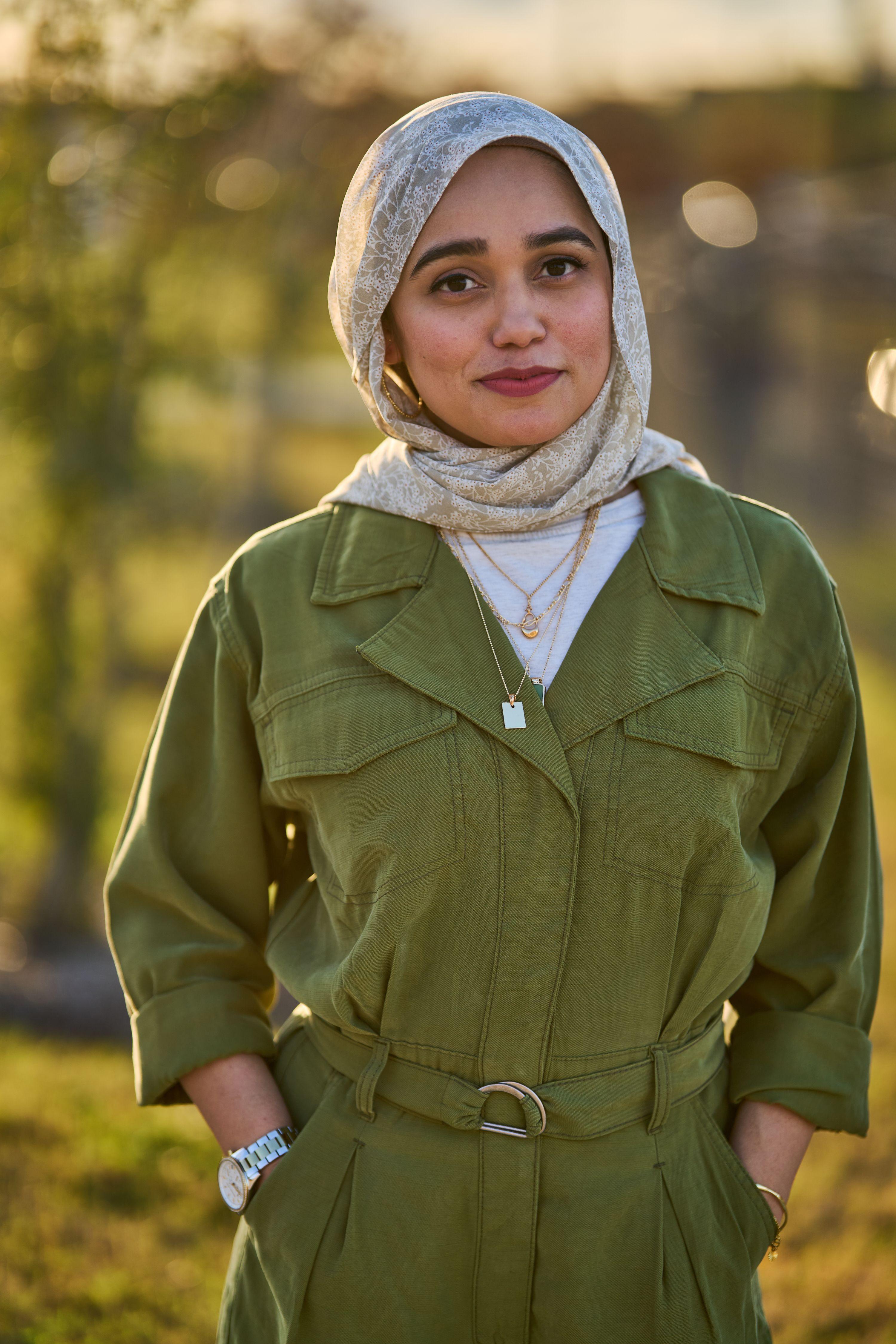 Woman in a headscarf and olive utility jumpsuit photographed outdoors, autumn foliage blurred — Business headshots, Austin A woman in a headscarf and olive utility jumpsuit photographed outdoors, autumn foliage blurred behind her