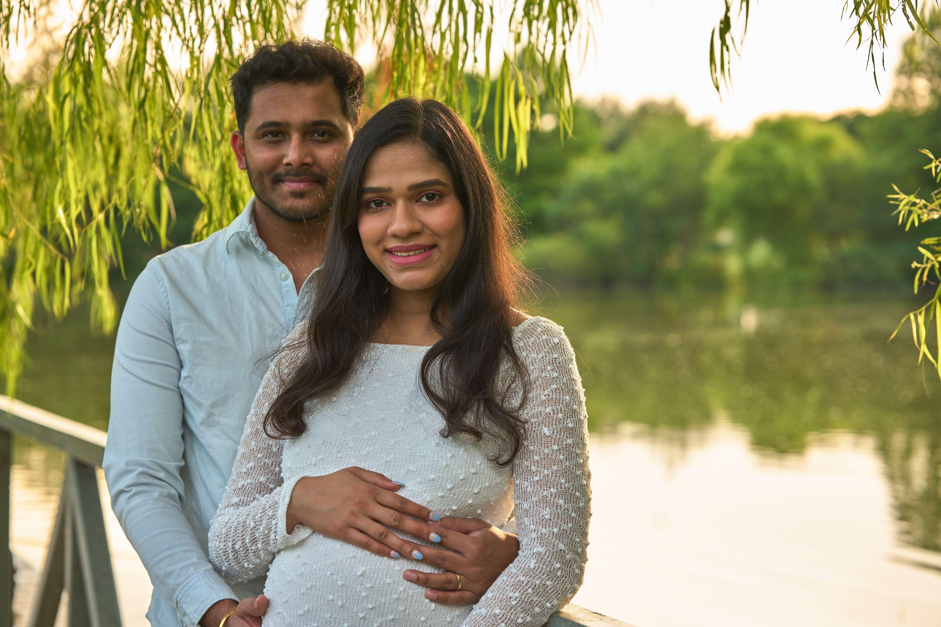 Expectant couple standing under the willows at the water's edge at Mills Pond — Mills Pond photography, Austin An expectant couple standing under the willows at the water's edge at Mills Pond