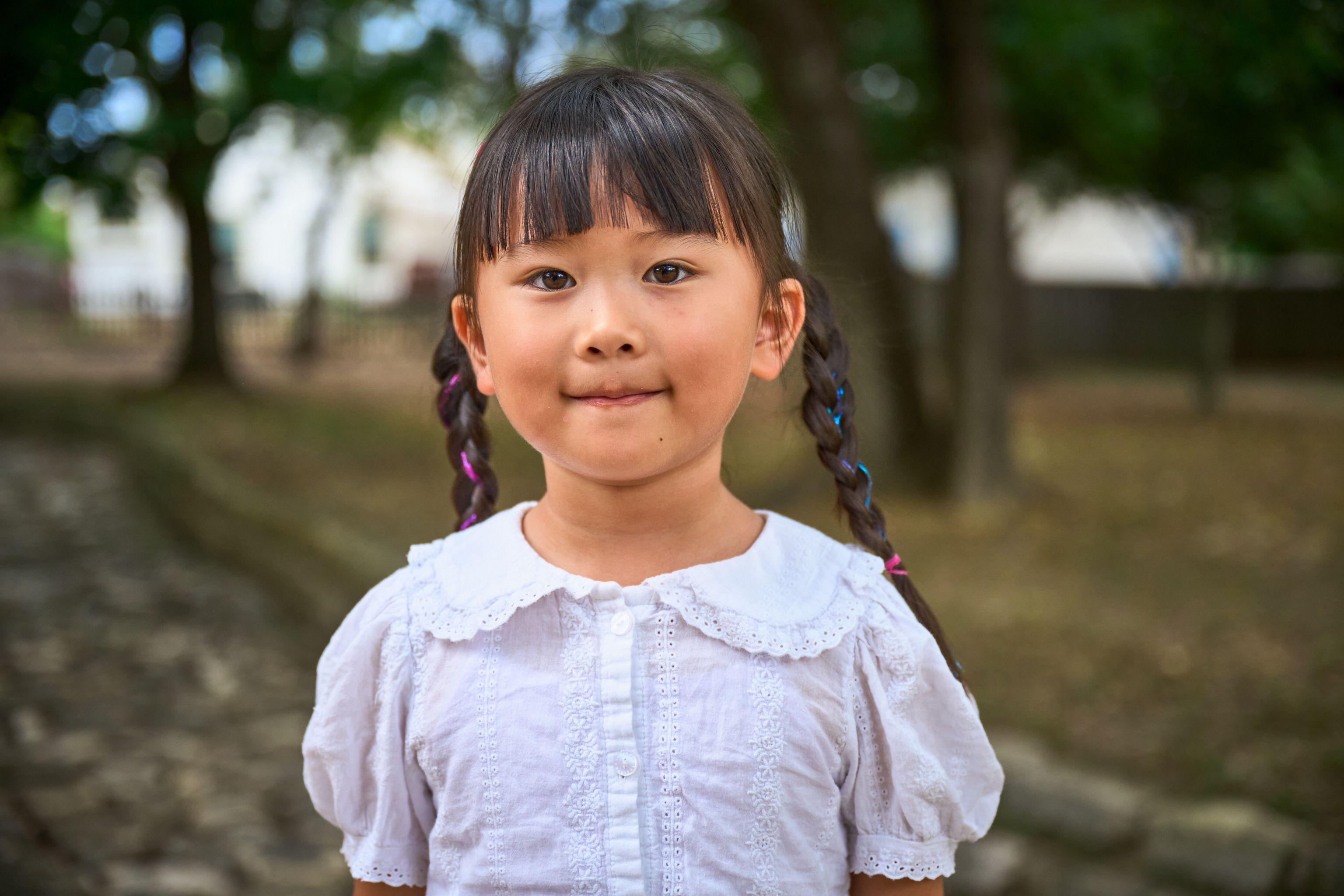 Girl with plaits and a white collared blouse smiling under a tree — Kids Portraits photography, Austin A girl with plaits and a white collared blouse smiling under a tree.