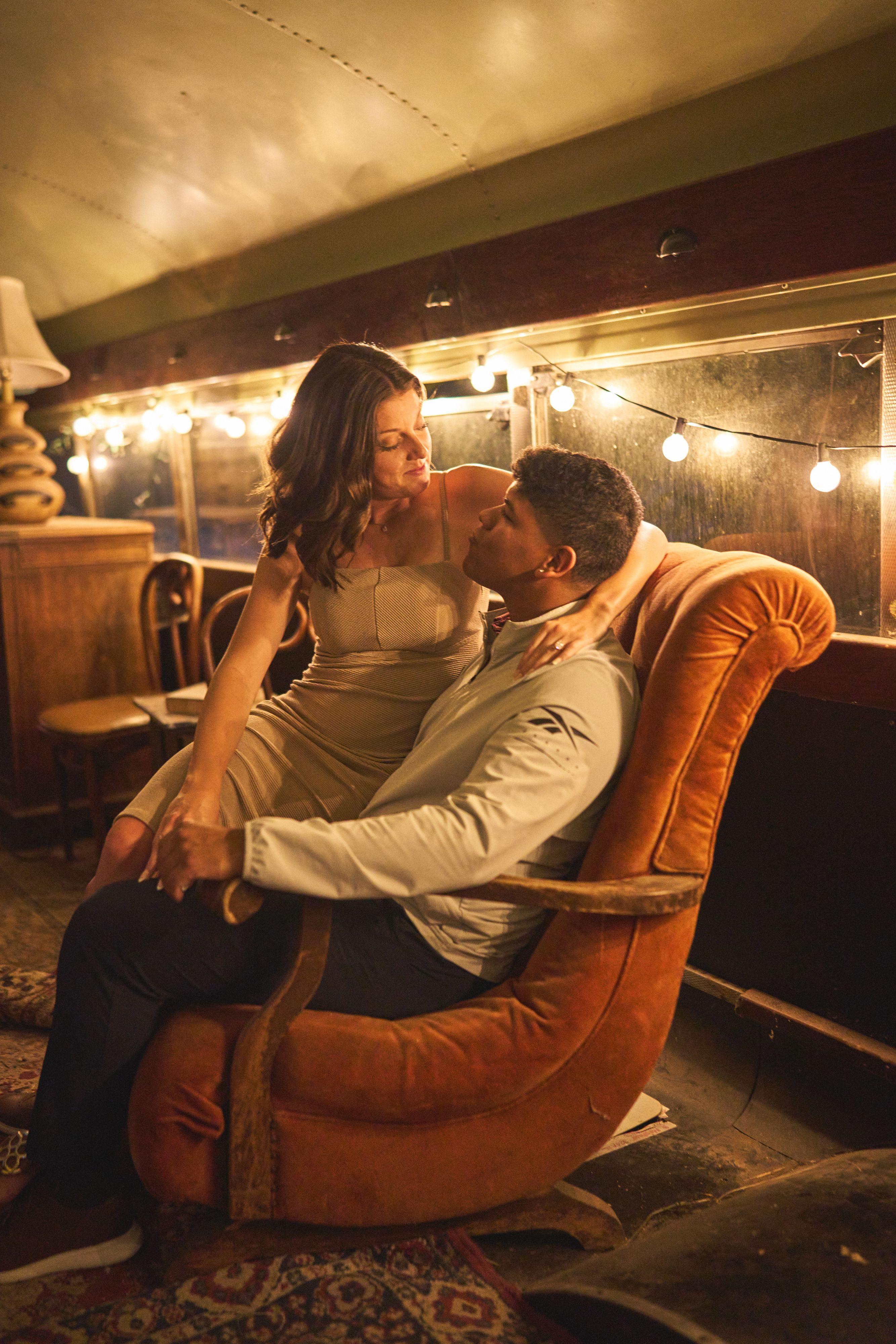 Couple sitting together in an orange velvet chair under string lights at Sekrit Theater — Sekrit Theater photography, Austin A couple sitting together in an orange velvet chair under string lights at Sekrit Theater