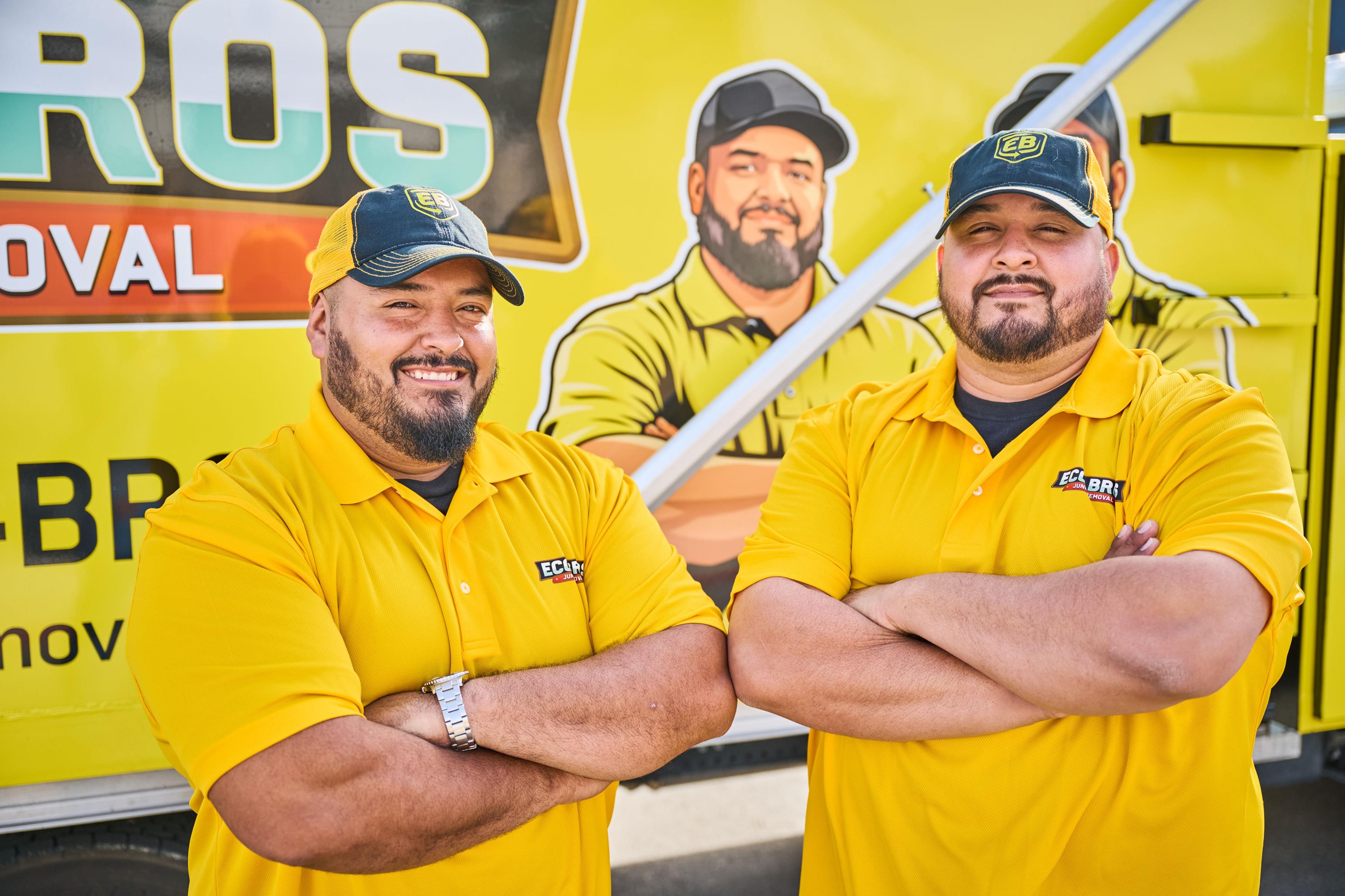 Three Eco Bros Junk Removal crew members in yellow polos with arms folded — Industrial photography, Austin Three Eco Bros Junk Removal crew members in yellow polos with arms folded in front of a branded wall