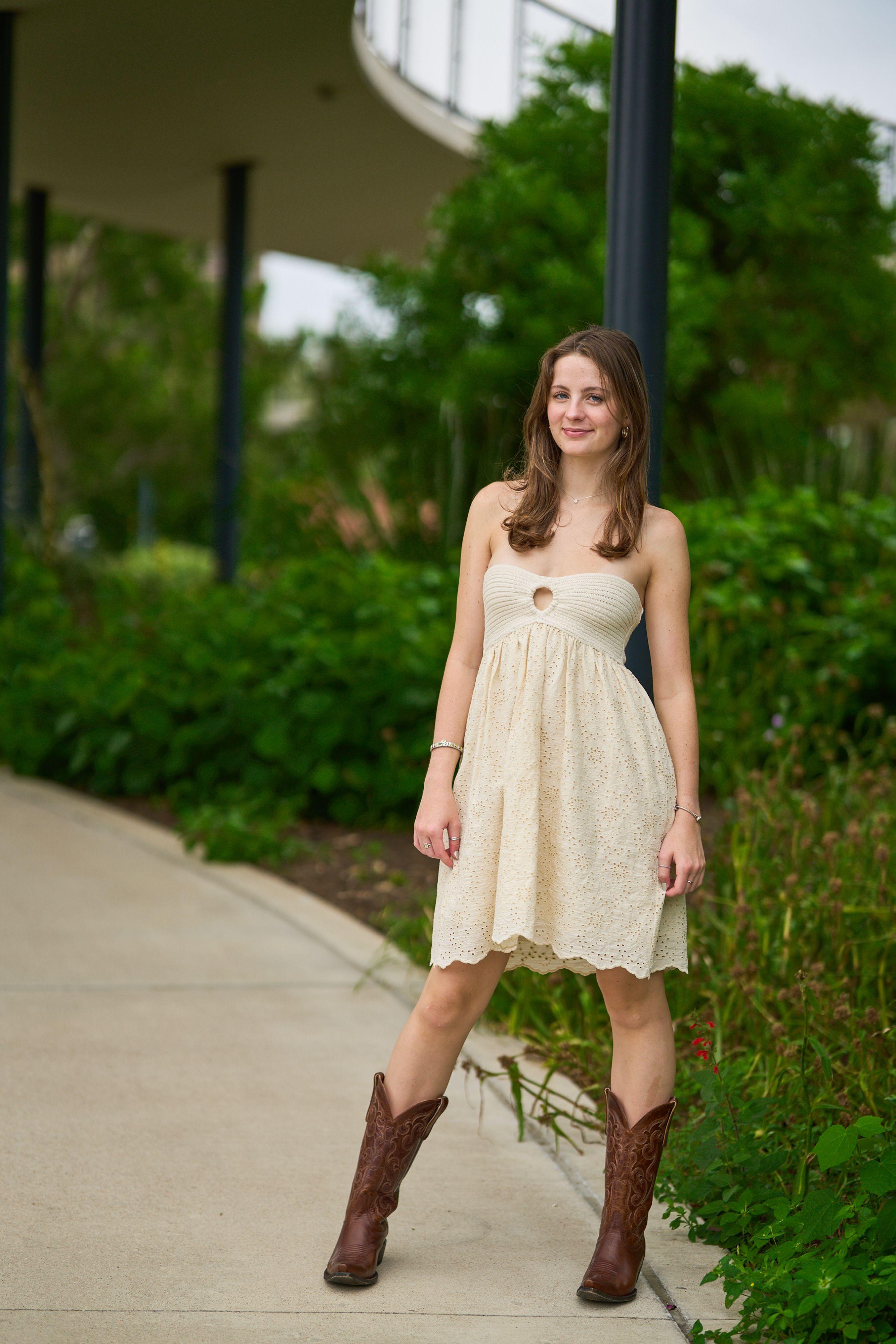 Young woman in a cream dress and cowboy boots walking a curved park path — Waterloo Park photography, Austin A young woman in a cream dress and cowboy boots walking a curved park path.