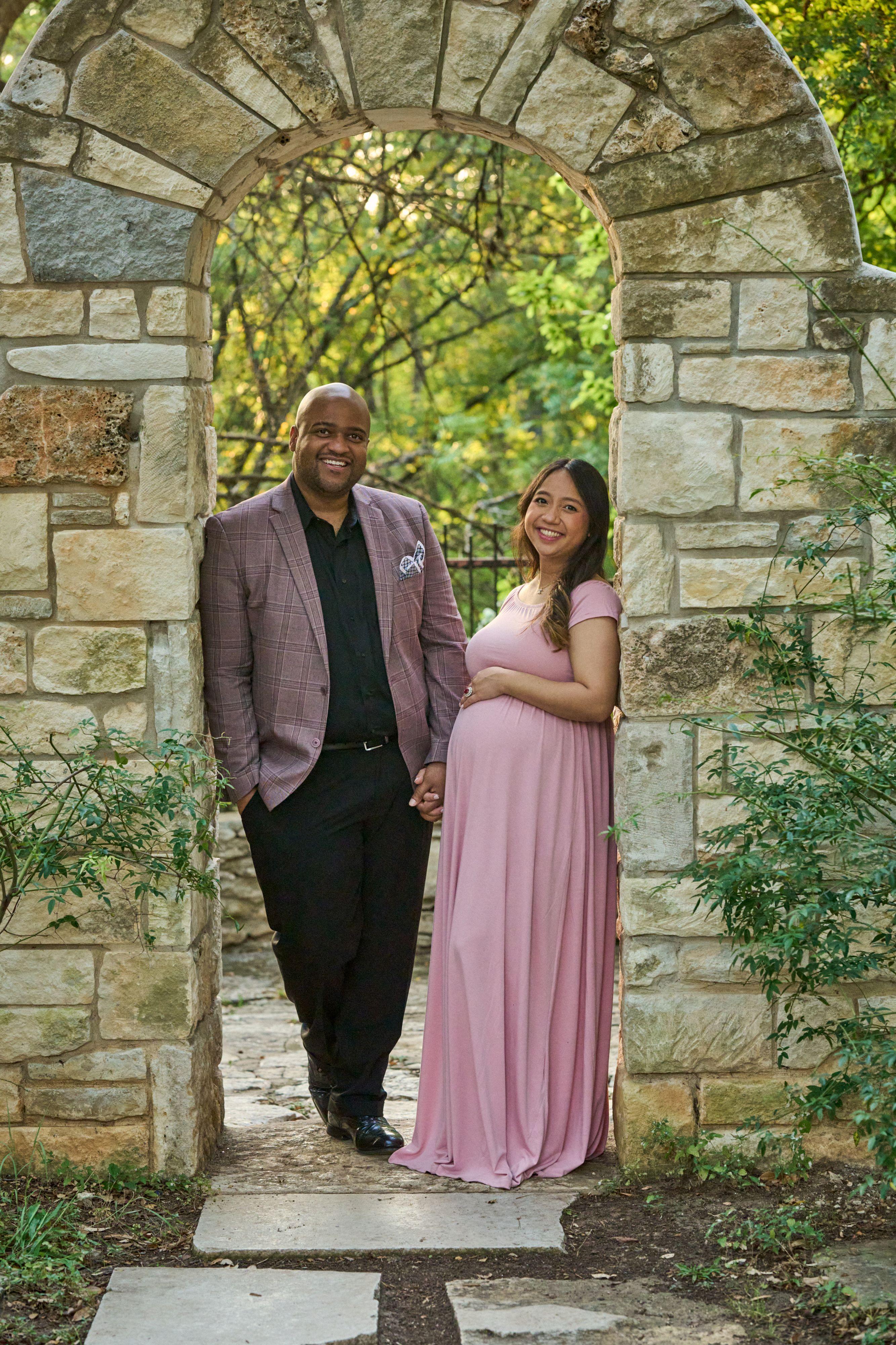 Expectant couple standing in the arched stone gateway at Mayfield Park — Mayfield Park photography, Austin An expectant couple standing in the arched stone gateway at Mayfield Park