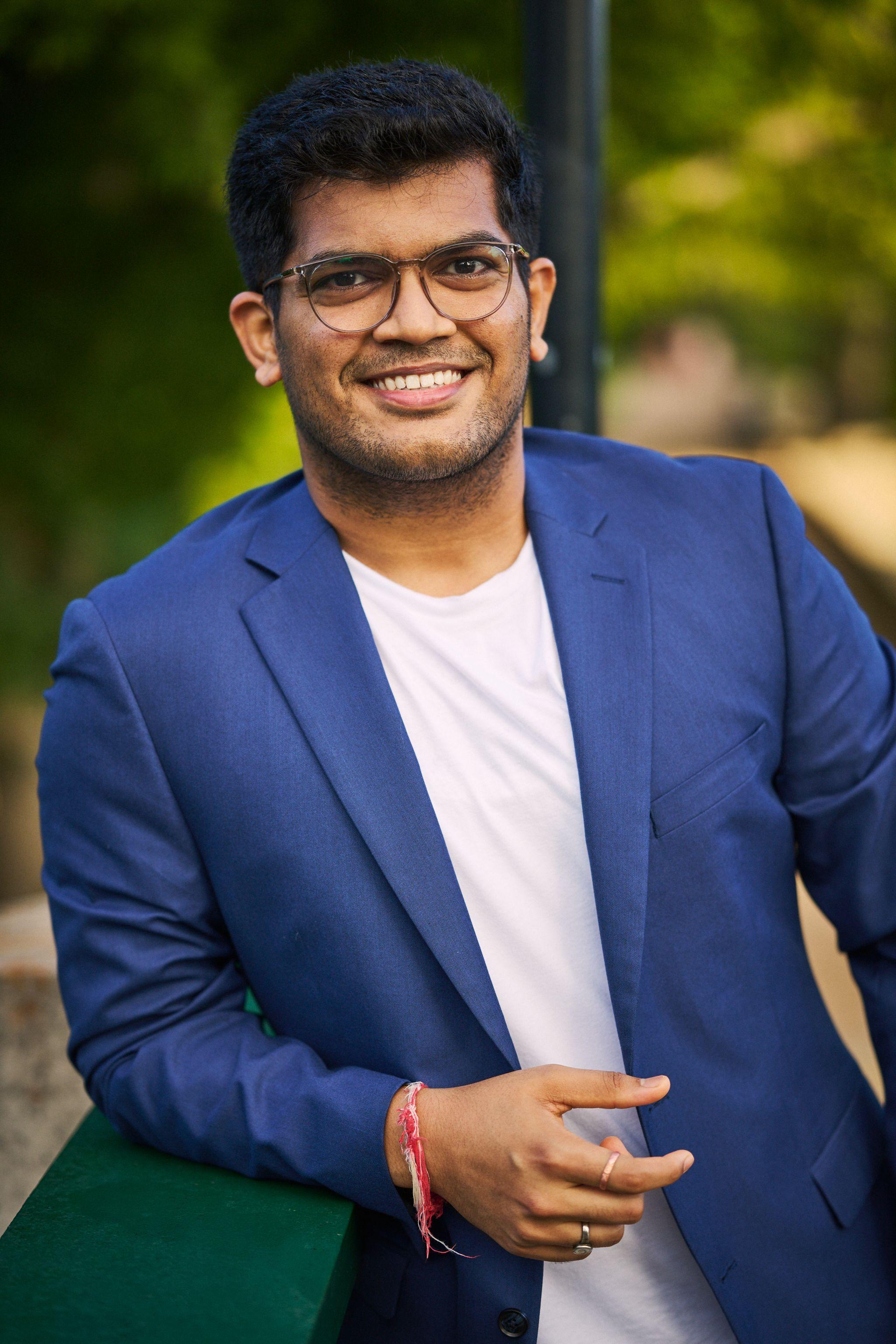 Man in a blue blazer and glasses smiling outdoors — Headshot photography, Austin A man in a blue blazer and glasses smiling outdoors.
