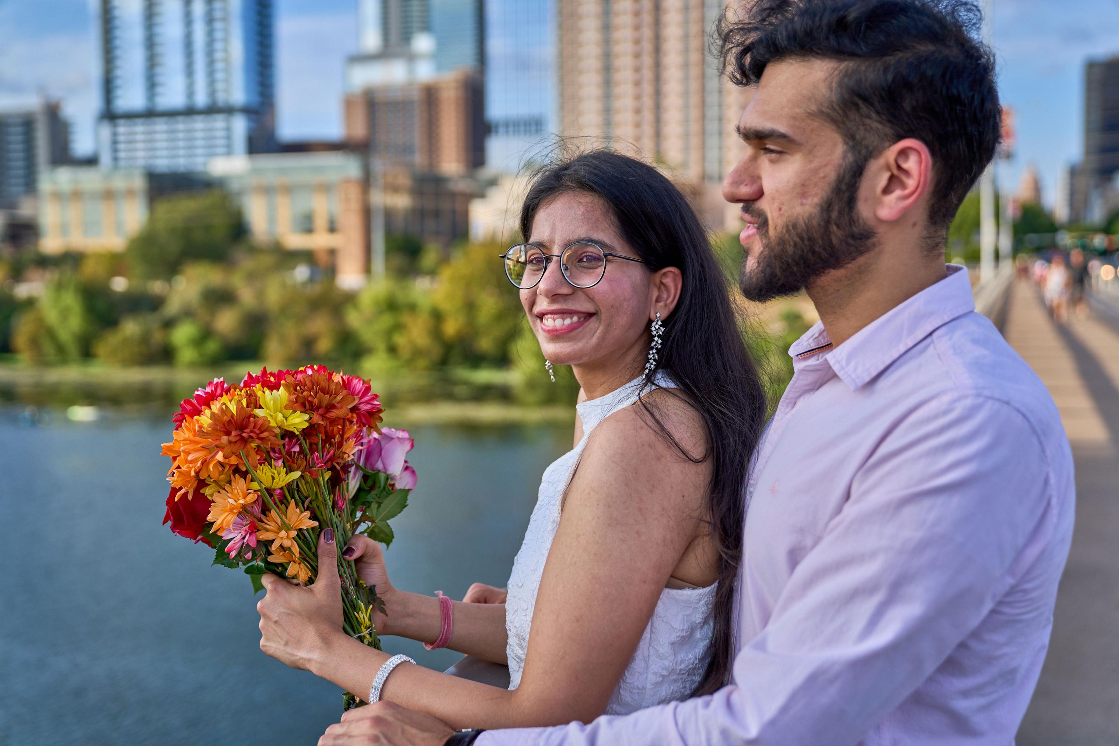 Couple looking at each other by Lady Bird Lake, the bride holding orange and pink flowers — Congress Avenue photography, Austin A couple looking at each other by Lady Bird Lake, the bride holding orange and pink flowers.