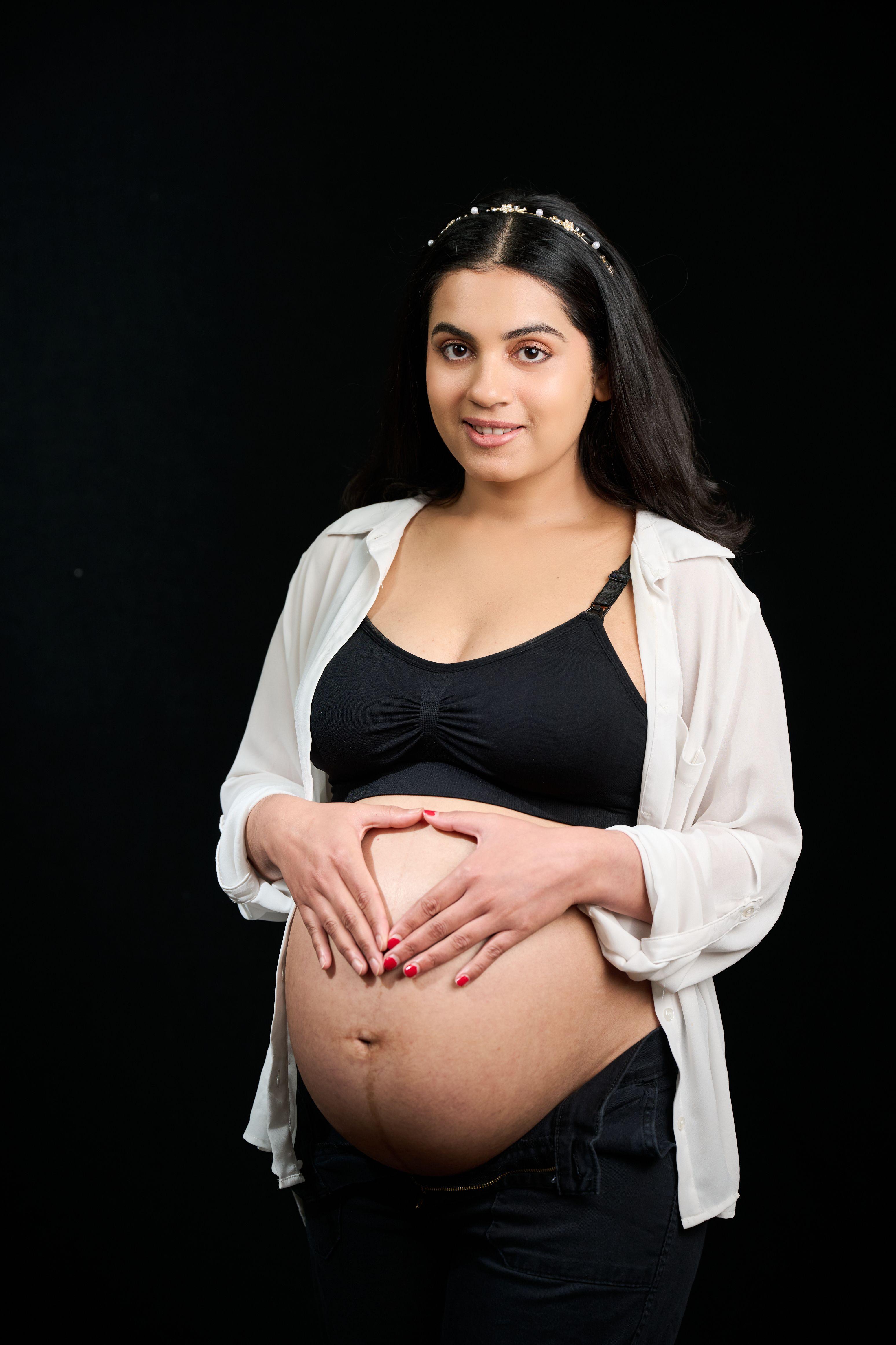 Expectant mother in an open white shirt against a dark studio background — Maternity photography, Austin Expectant mother in an open white shirt against a dark studio background