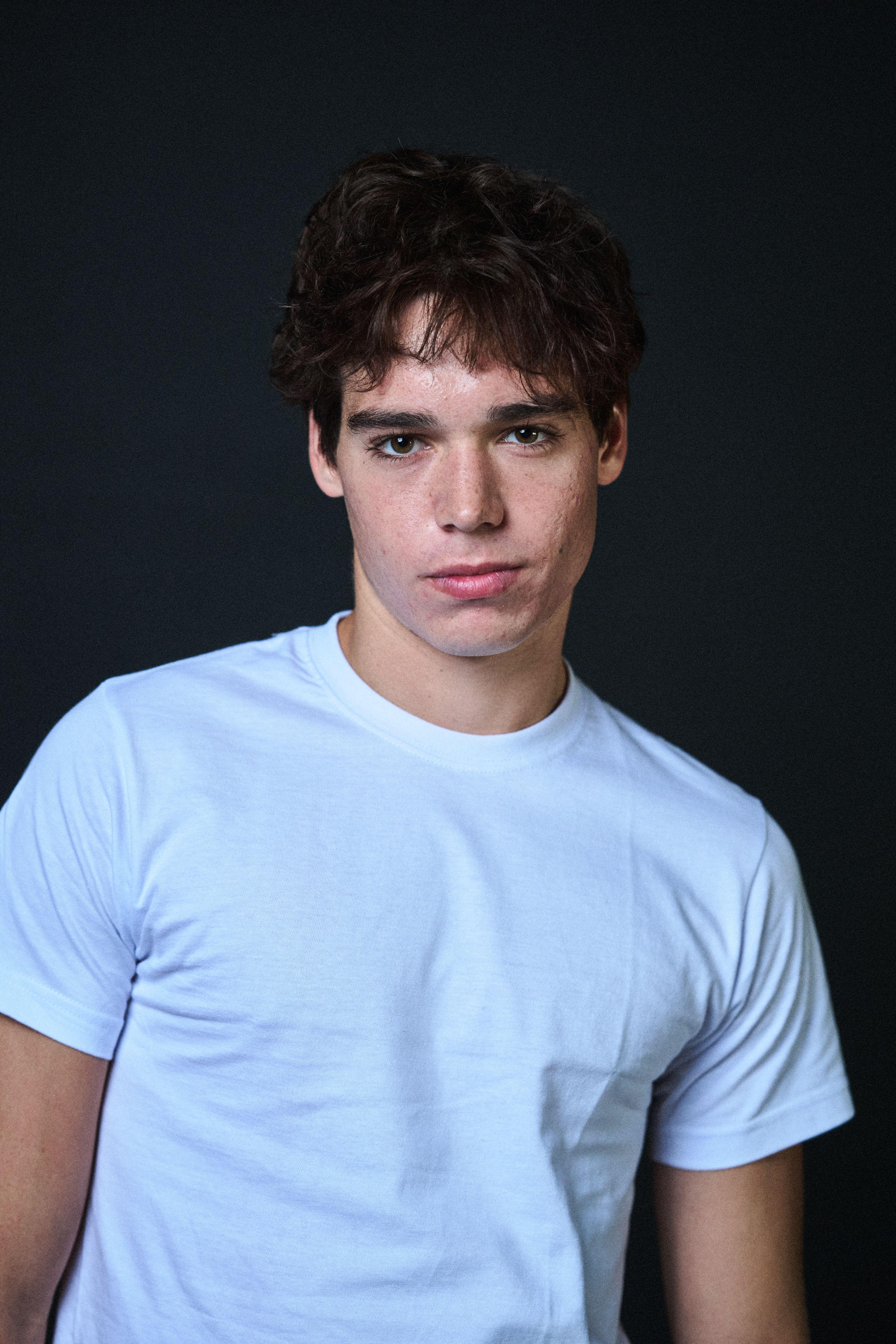 Young actor in a pale blue t-shirt against a dark studio background — Headshot photography, Austin A young actor in a pale blue t-shirt against a dark studio background.
