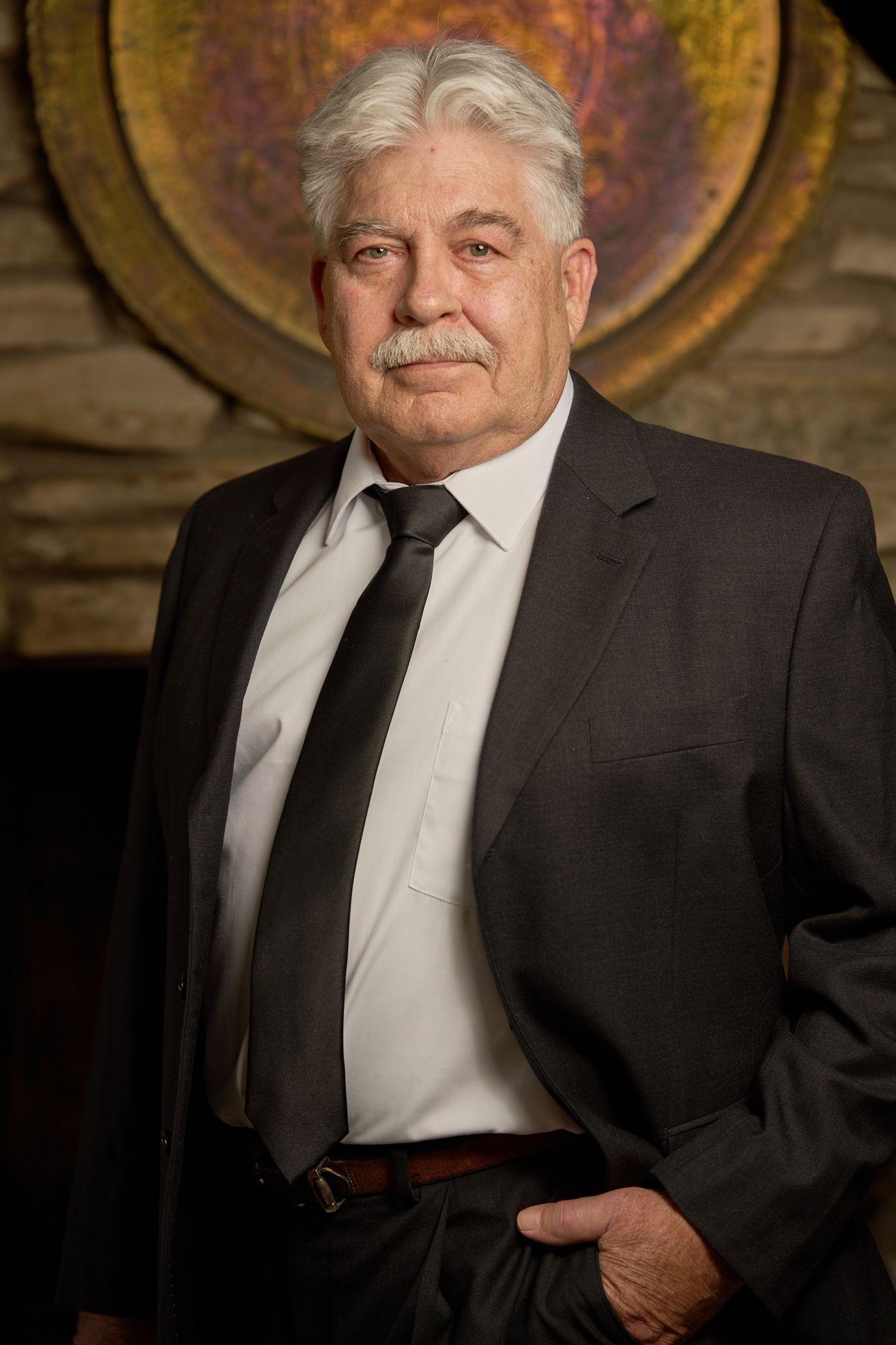 Older man in a dark suit and tie photographed indoors — Headshot photography, Austin An older man in a dark suit and tie photographed indoors.