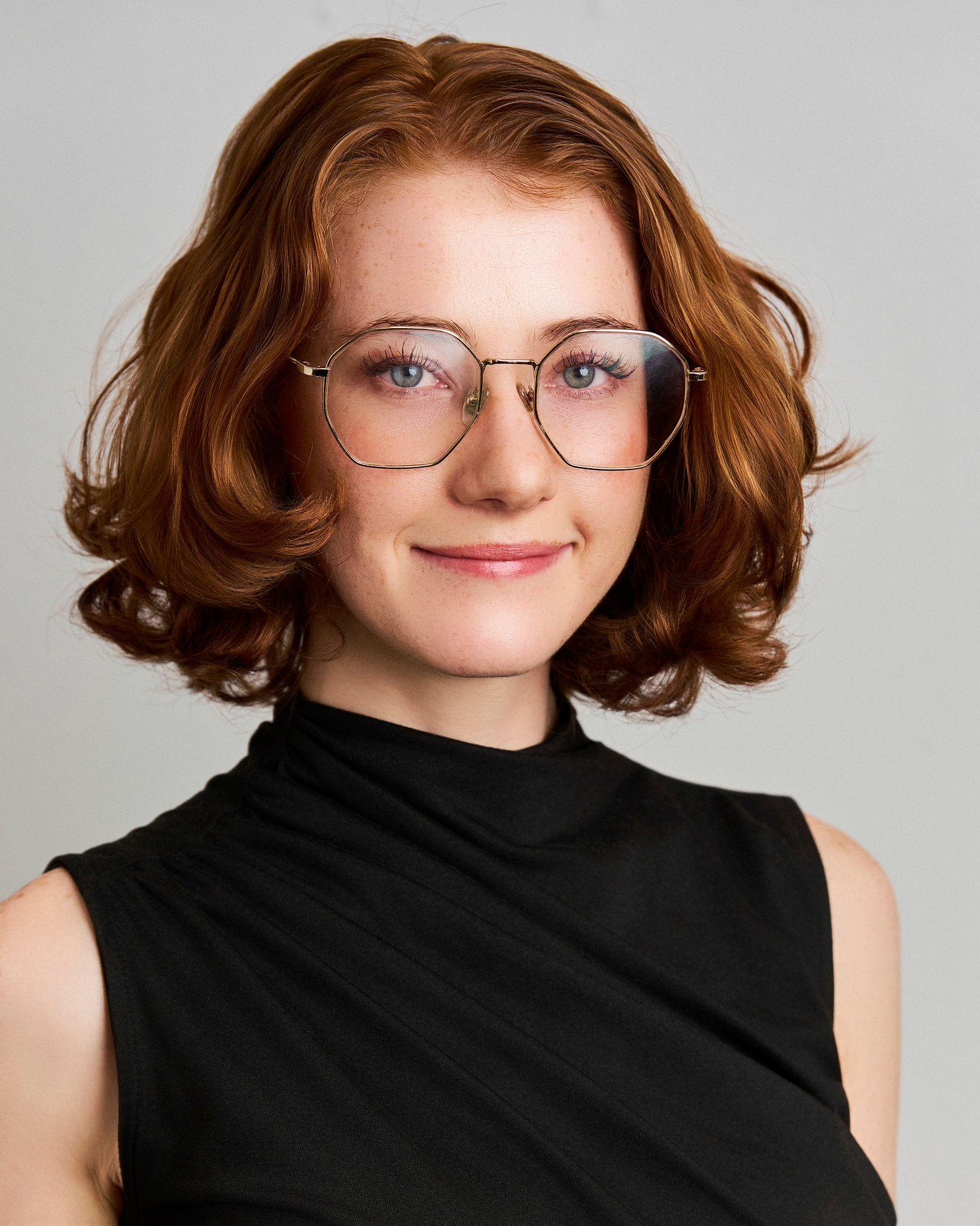 Red-haired woman in glasses and a black turtleneck against a gray studio background — Photo retouching, Austin A red-haired woman in glasses and a black turtleneck against a gray studio background.