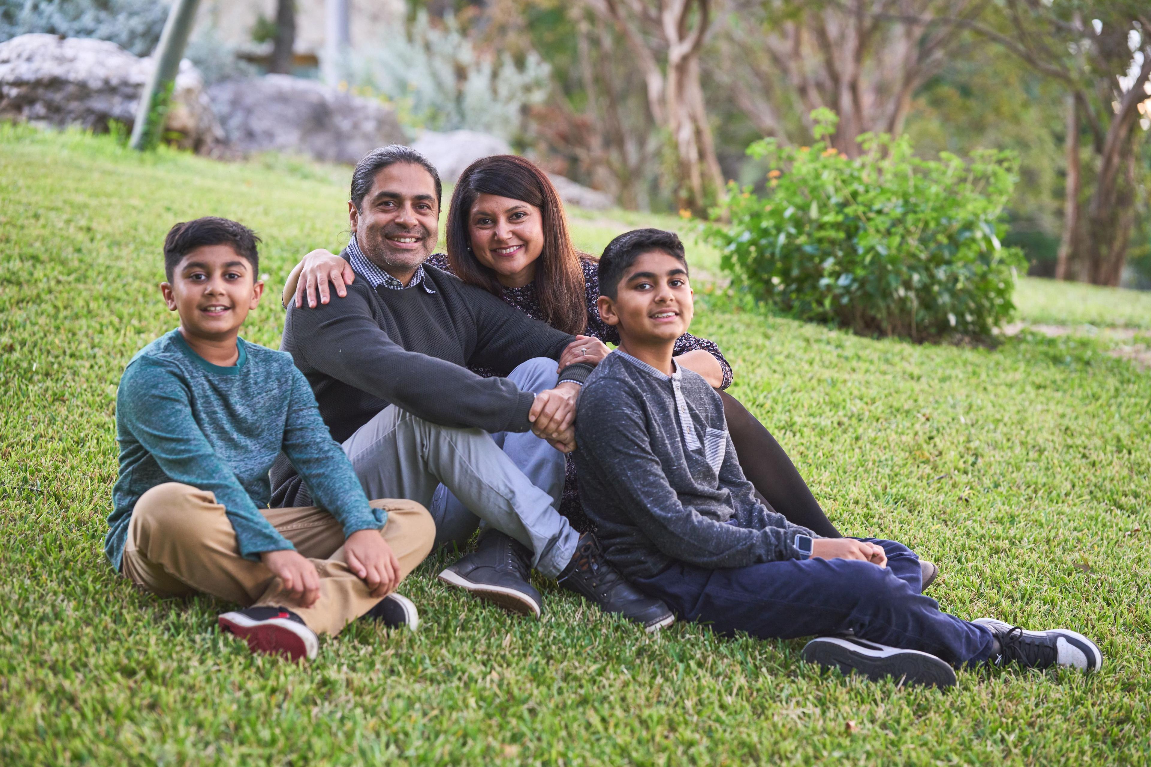 Family sitting together on the grass slope at Olson Meadows Park, laughing — Olson Meadows Park photography, Austin A family sitting together on the grass slope at Olson Meadows Park, laughing