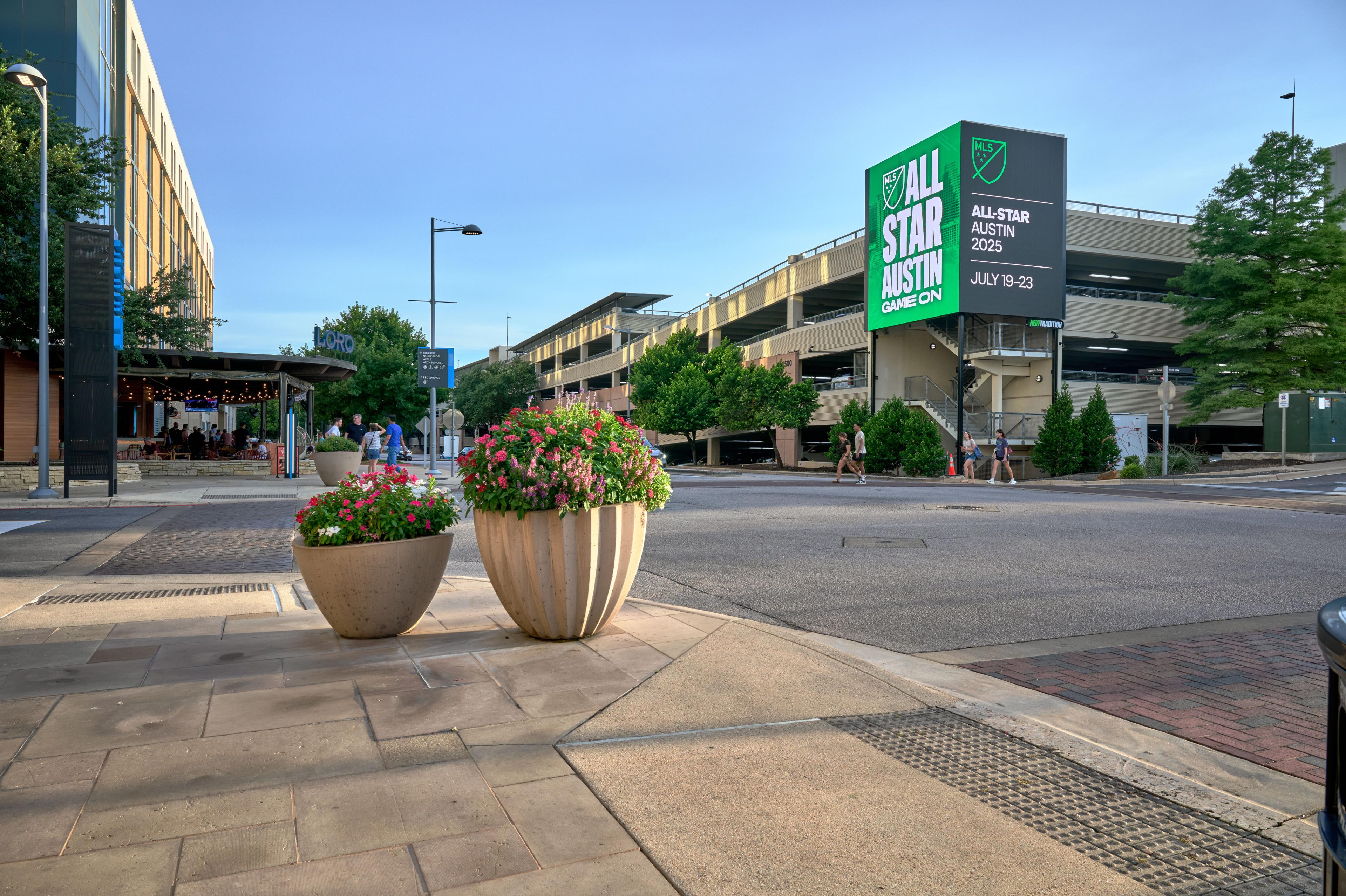 Green NBA All-Star Austin 2025 billboard mounted on a parking garage — Outdoor media photography, Austin A green NBA All-Star Austin 2025 billboard mounted on a parking garage above a quiet street corner.