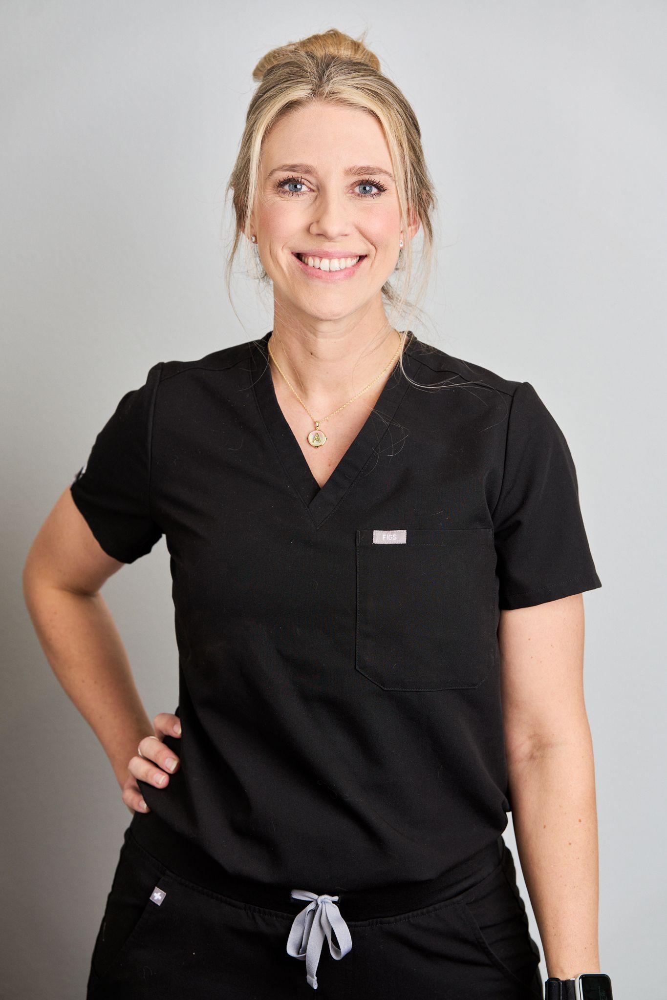 Practitioner in black scrubs standing with a hand on her hip against a white studio background — Medical team photography, Austin Practitioner in black scrubs standing with a hand on her hip against a white studio background