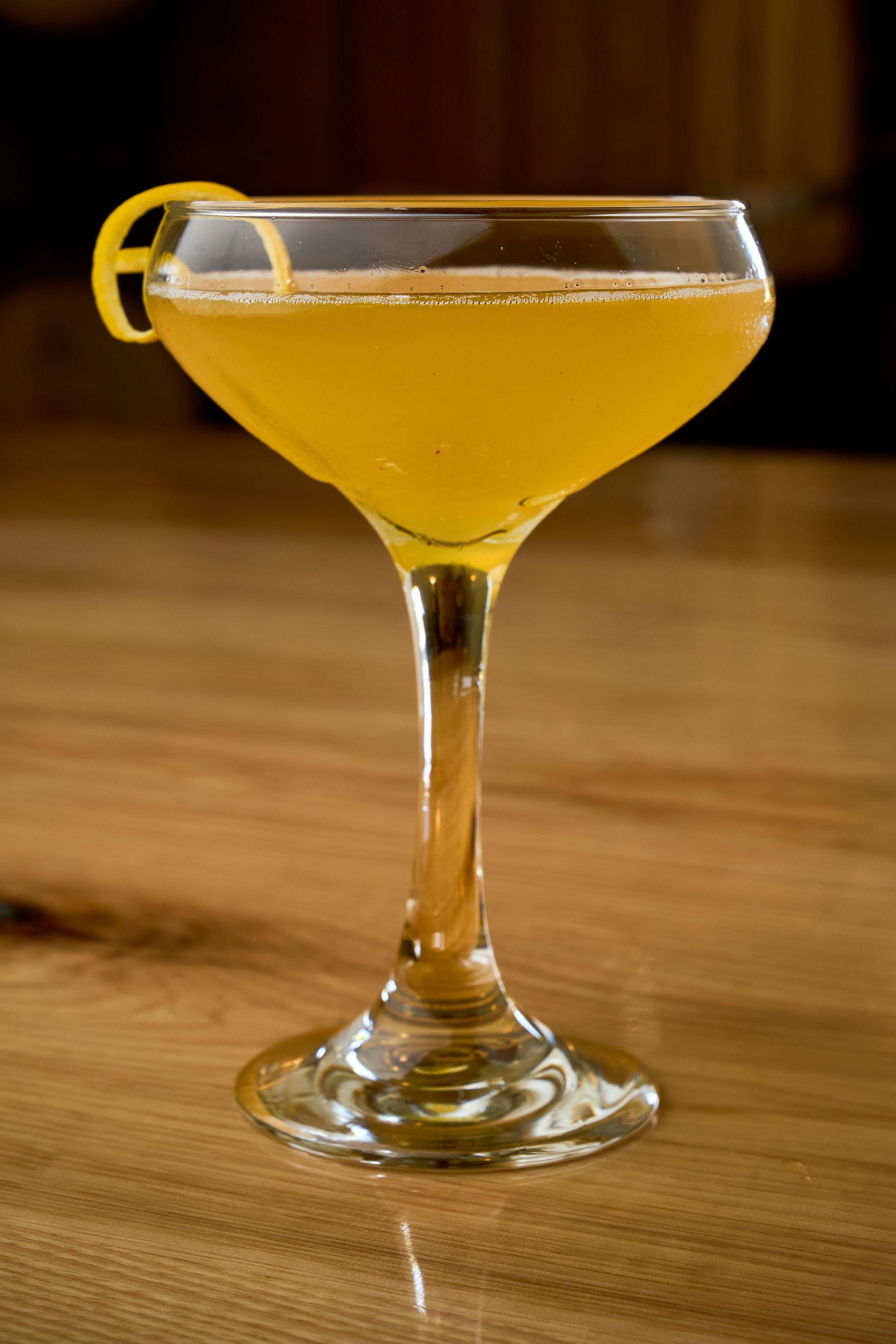 Coupe cocktail with a citrus twist on a wooden bar — Food & restaurant photography, Austin A coupe cocktail with a citrus twist on a wooden bar.