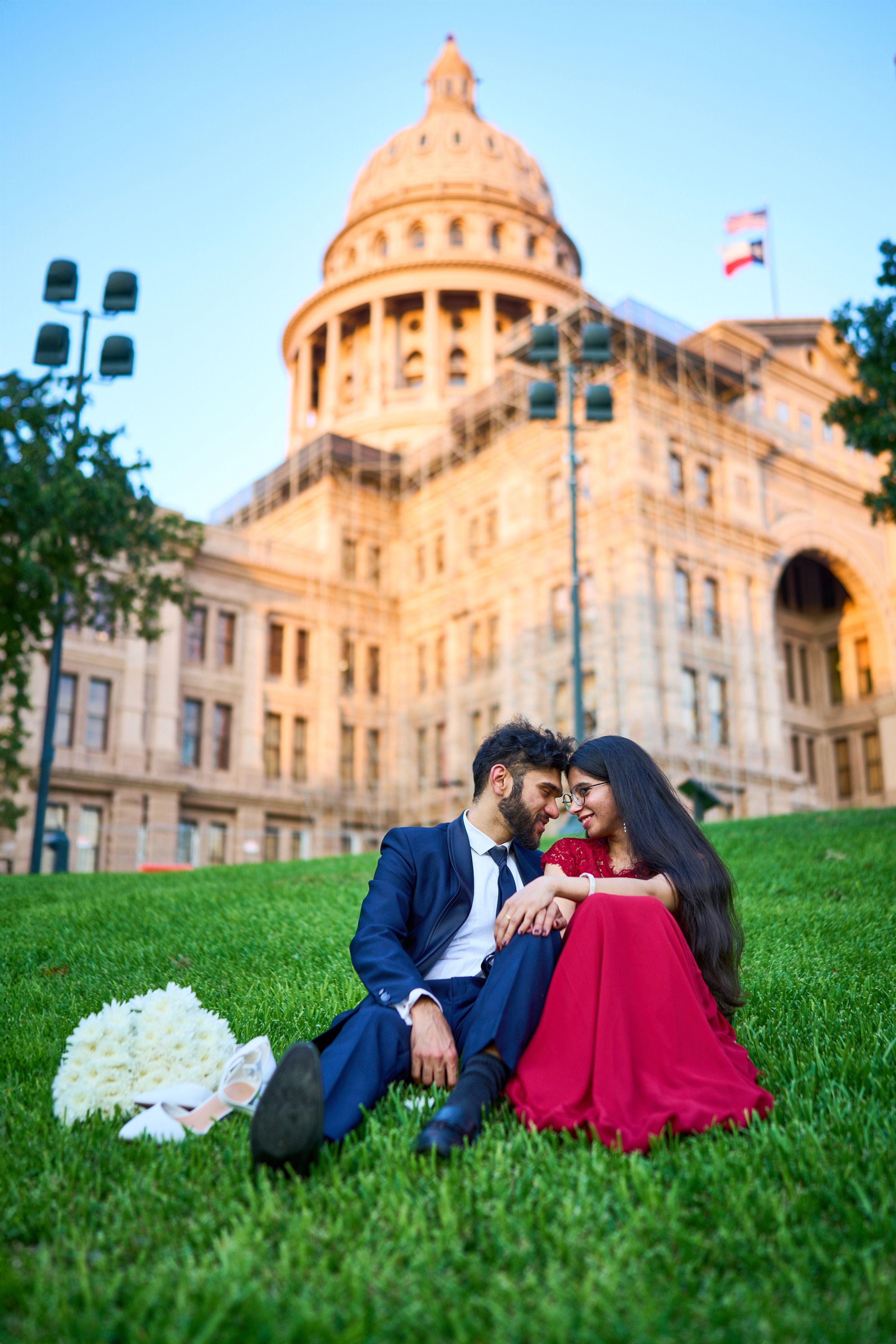 Couple seated on the Texas Capitol lawn, the bride in a red gown, the dome lit behind them — Elopements photography, Austin A couple seated on the Texas Capitol lawn, the bride in a red gown, the dome lit behind them.