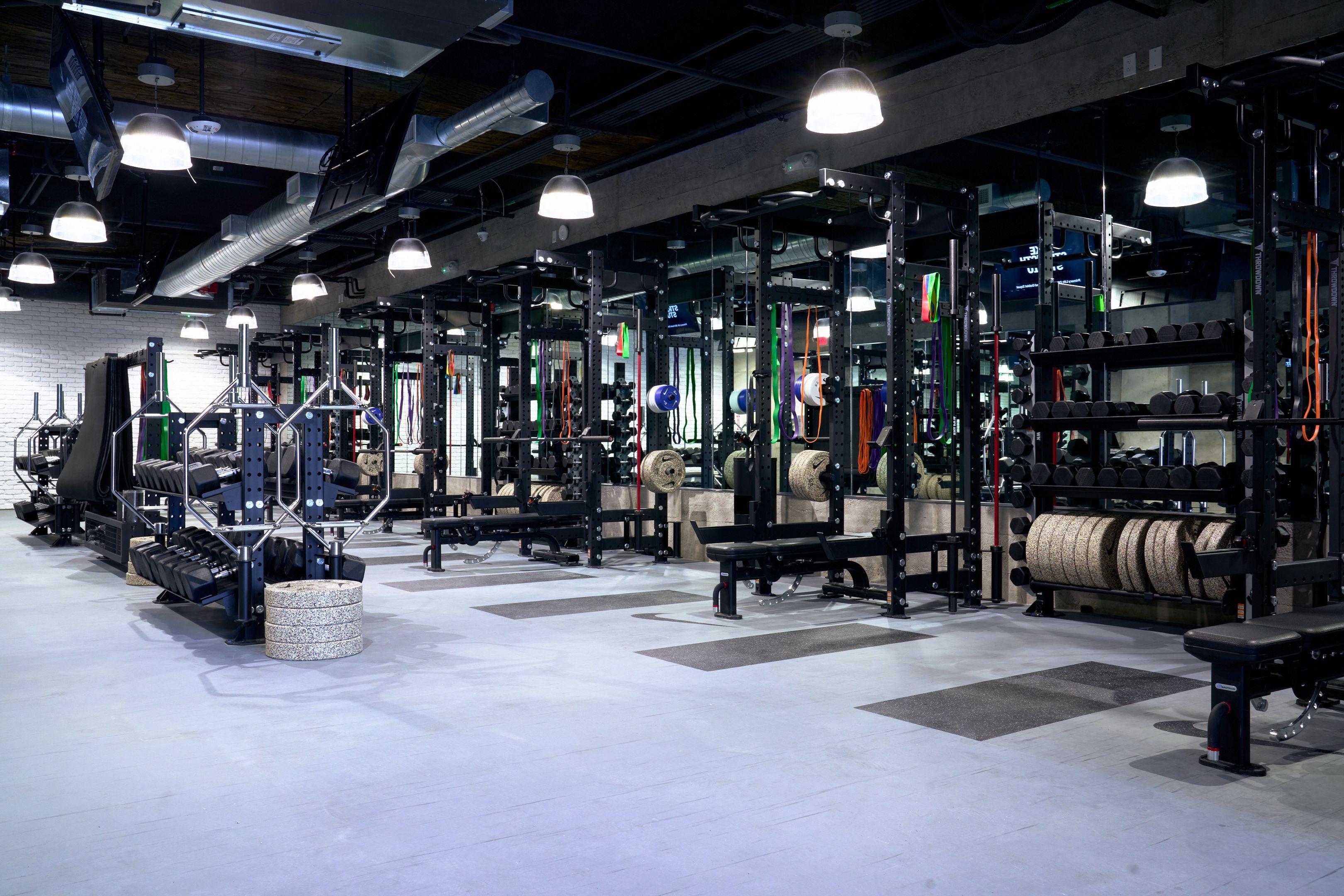 Empty strength and conditioning gym with squat racks, dumbbells and resistance bands — Sports photography, Austin Empty strength and conditioning gym with squat racks, dumbbells and resistance bands under industrial lighting