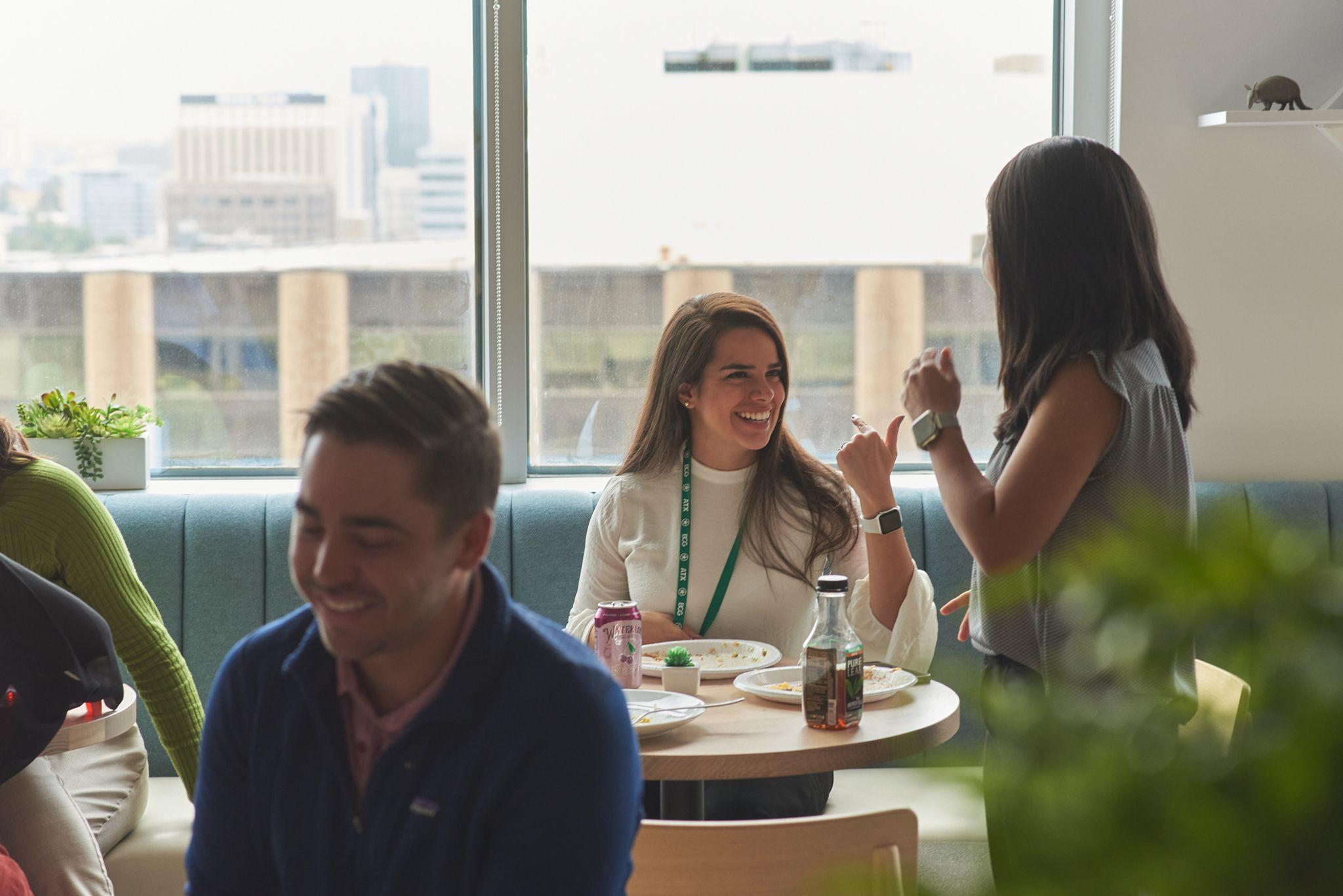 Colleagues laughing together in a booth beside a window at an offsite — Team offsite photography, Austin Colleagues laughing together in a booth beside a window at an offsite