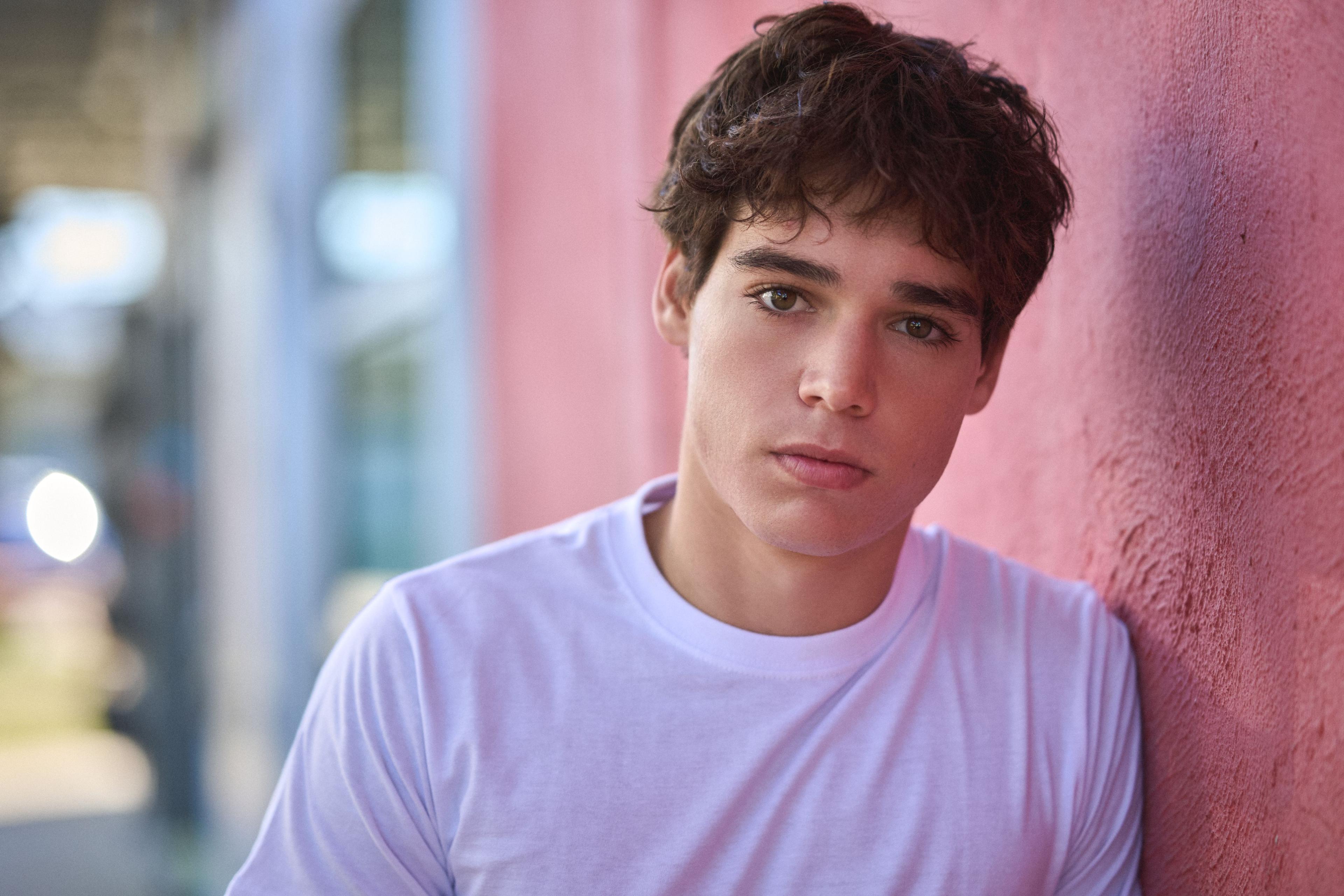 Male model in a lilac t-shirt leaning against a pink stucco wall — Fashion & editorial photography, Austin A male model in a lilac t-shirt leaning against a pink stucco wall.