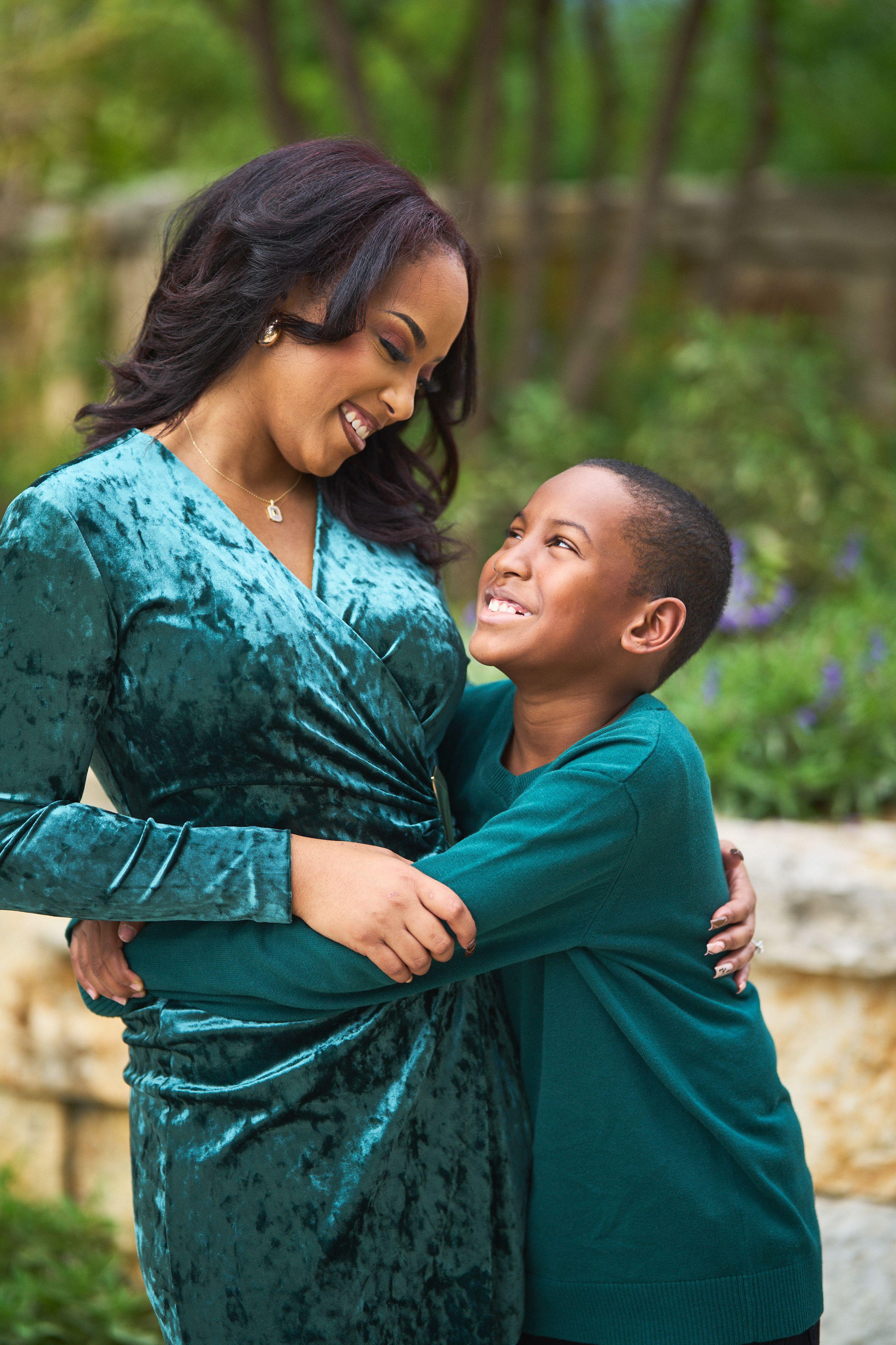Mother in green velvet laughing with her son, his arms around her waist — Seasonal Christmas & Fall photography, Austin A mother in green velvet laughing with her son, his arms around her waist.