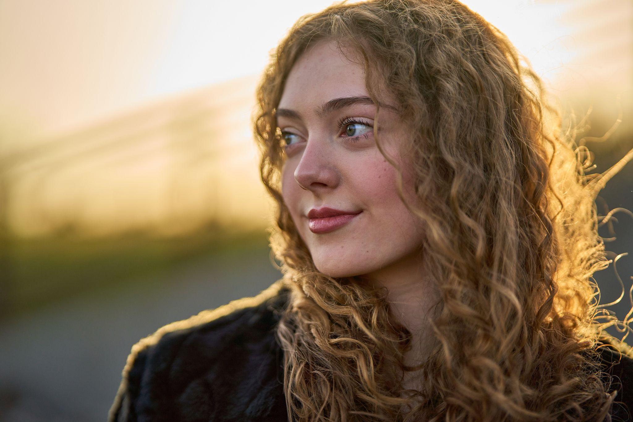 Close portrait of a young woman with curly hair looking off to the left in low golden light — Round Rock Old Settlers Park photography, Austin A close portrait of a young woman with curly hair looking off to the left in low golden light at Old Settlers Park